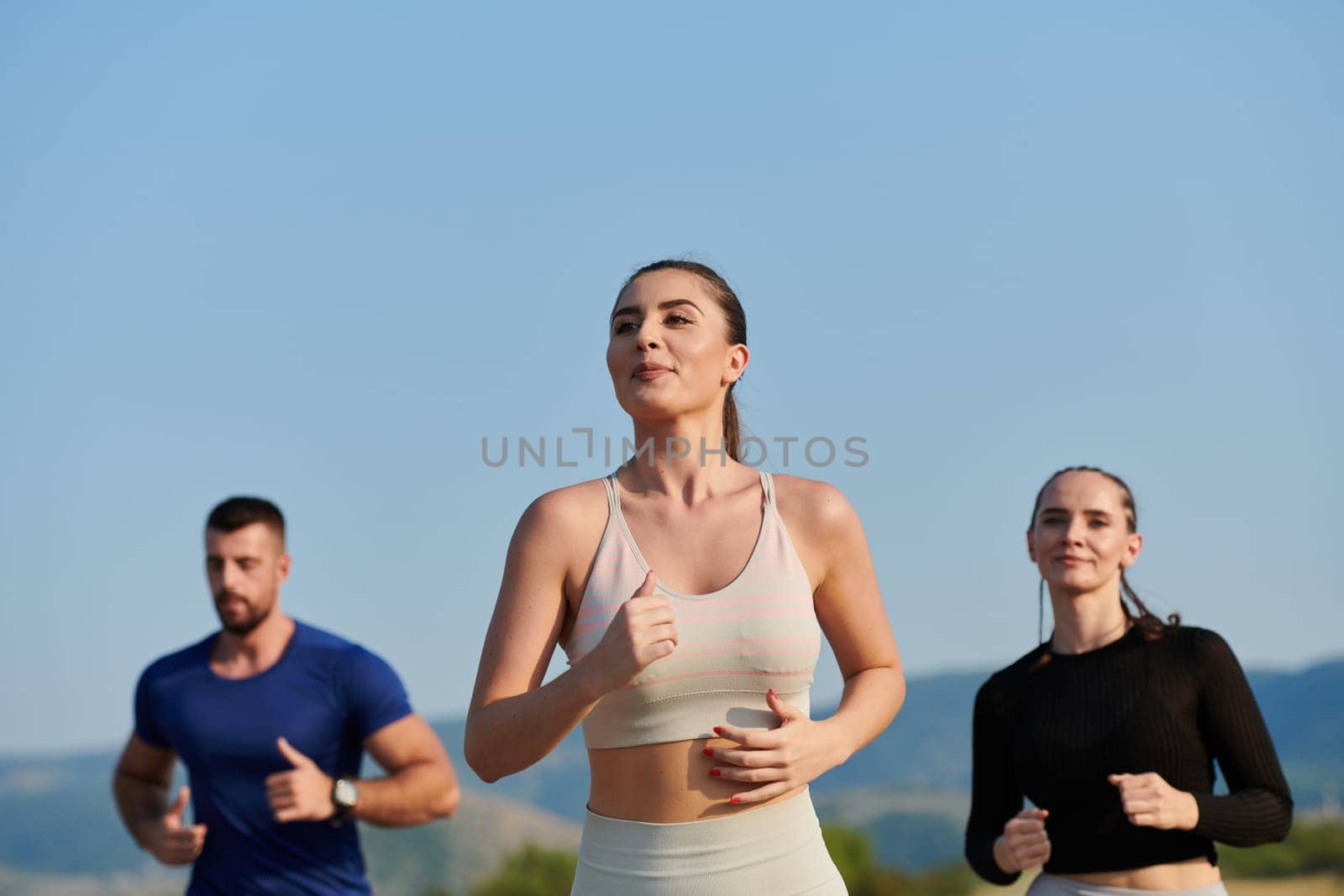 A group of friends maintains a healthy lifestyle by running outdoors on a sunny day, bonding over fitness and enjoying the energizing effects of exercise and nature by dotshock