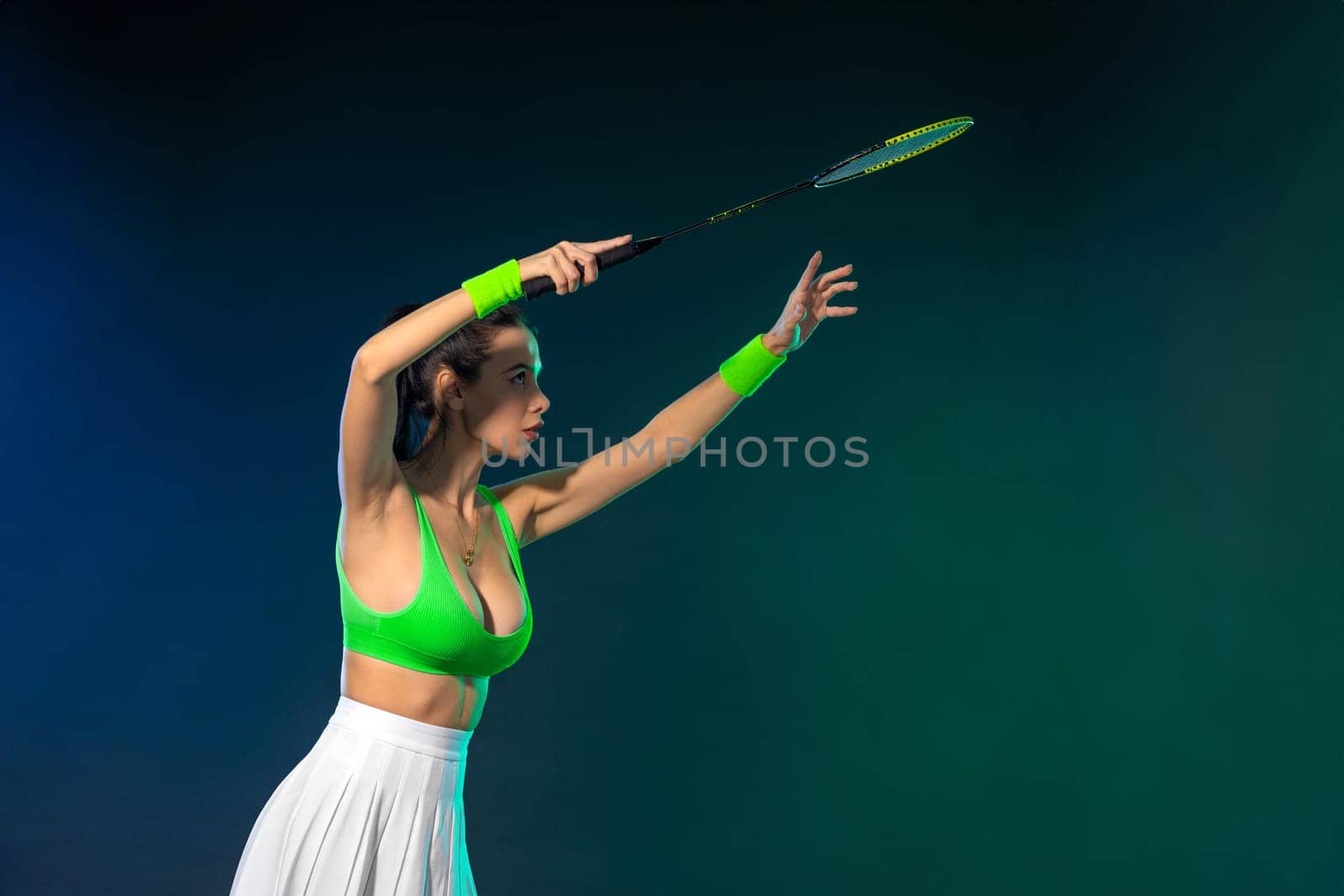 Badminton player in sport outfit reaching for a shuttle with a racket swing. Studio shoot.