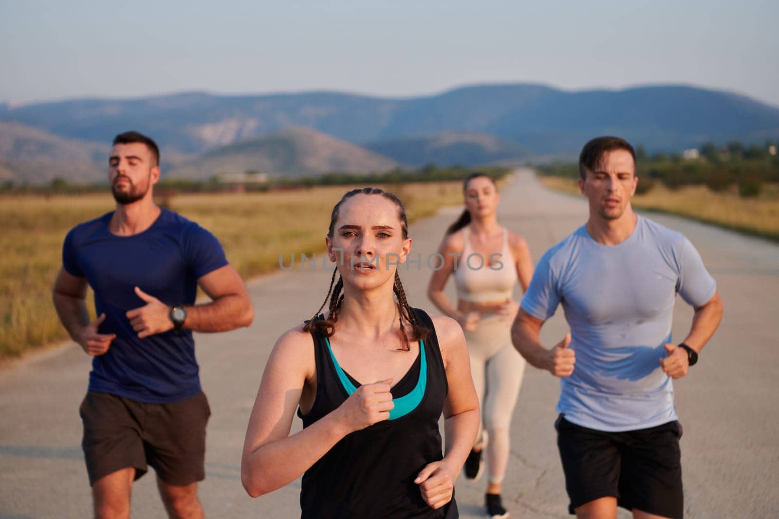 A group of friends maintains a healthy lifestyle by running outdoors on a sunny day, bonding over fitness and enjoying the energizing effects of exercise and nature by dotshock