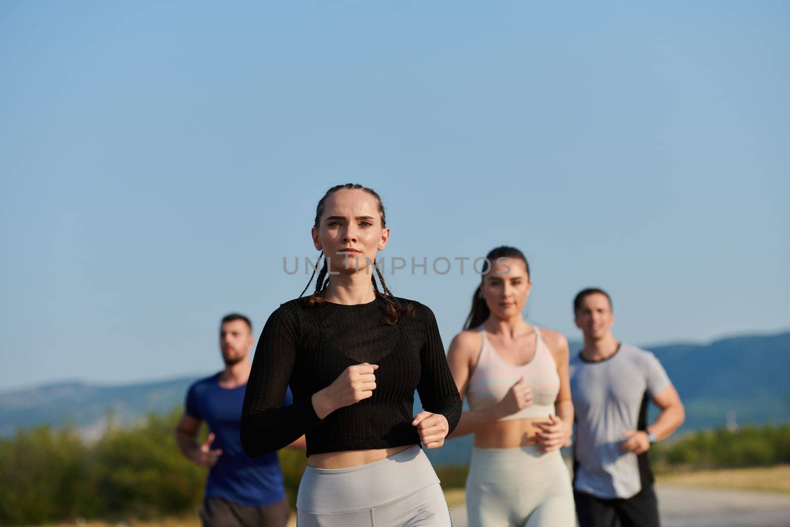 A group of friends maintains a healthy lifestyle by running outdoors on a sunny day, bonding over fitness and enjoying the energizing effects of exercise and nature by dotshock