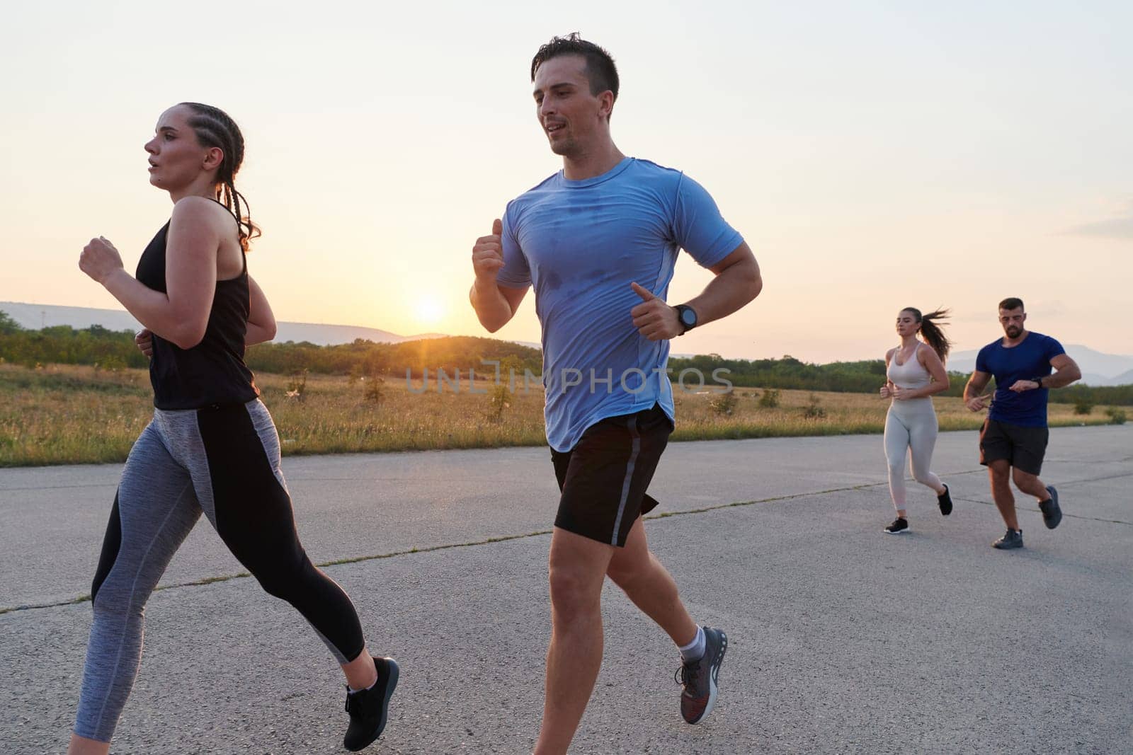 A diverse group of runners finds motivation and inspiration in each other as they train together for an upcoming competition, set against a breathtaking sunset backdrop.