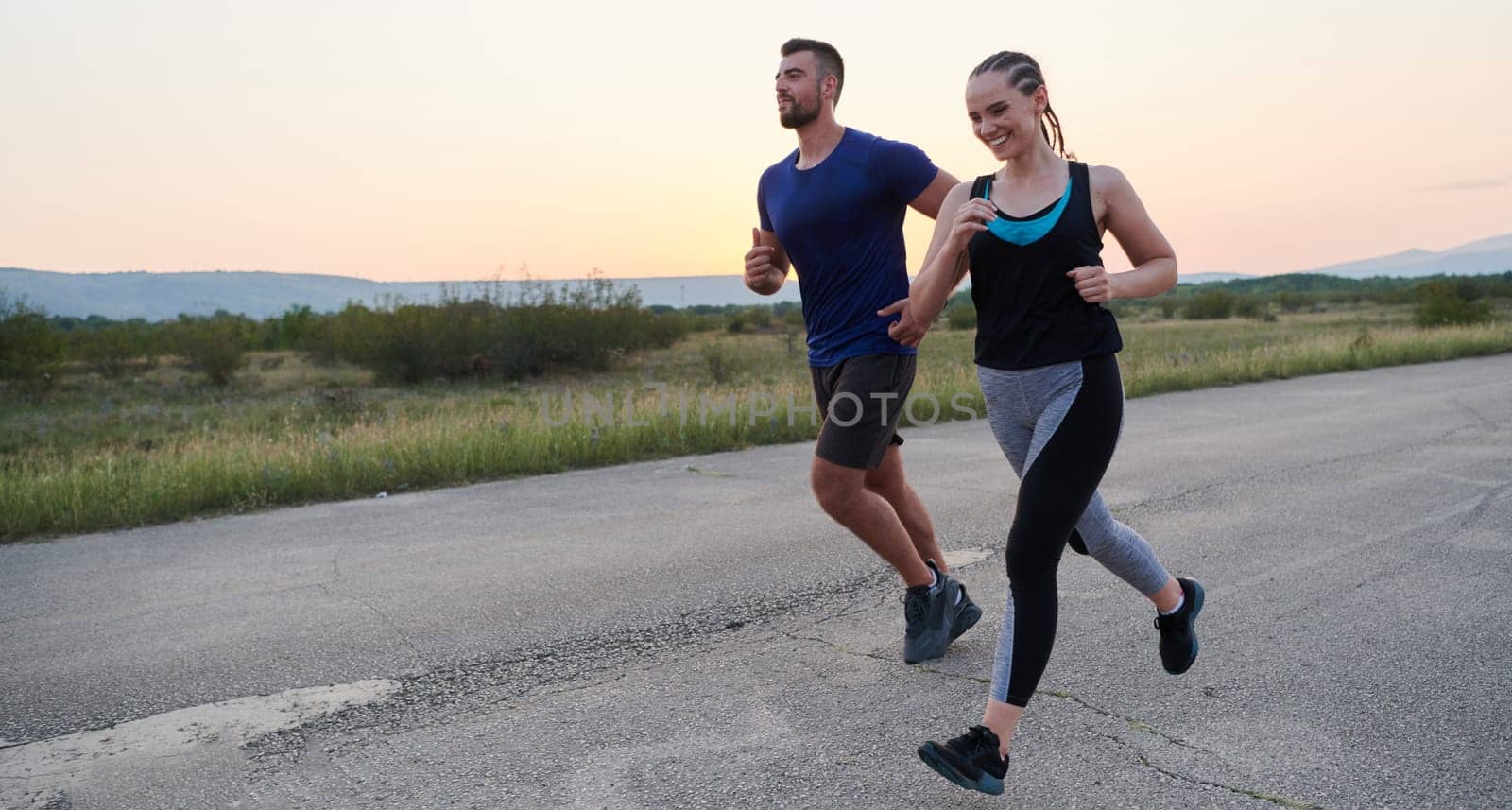 A vibrant couple dashes running the outdoors, embodying the essence of athleticism and romance, their confident strides reflecting a shared commitment to fitness and preparation for future marathon challenges.