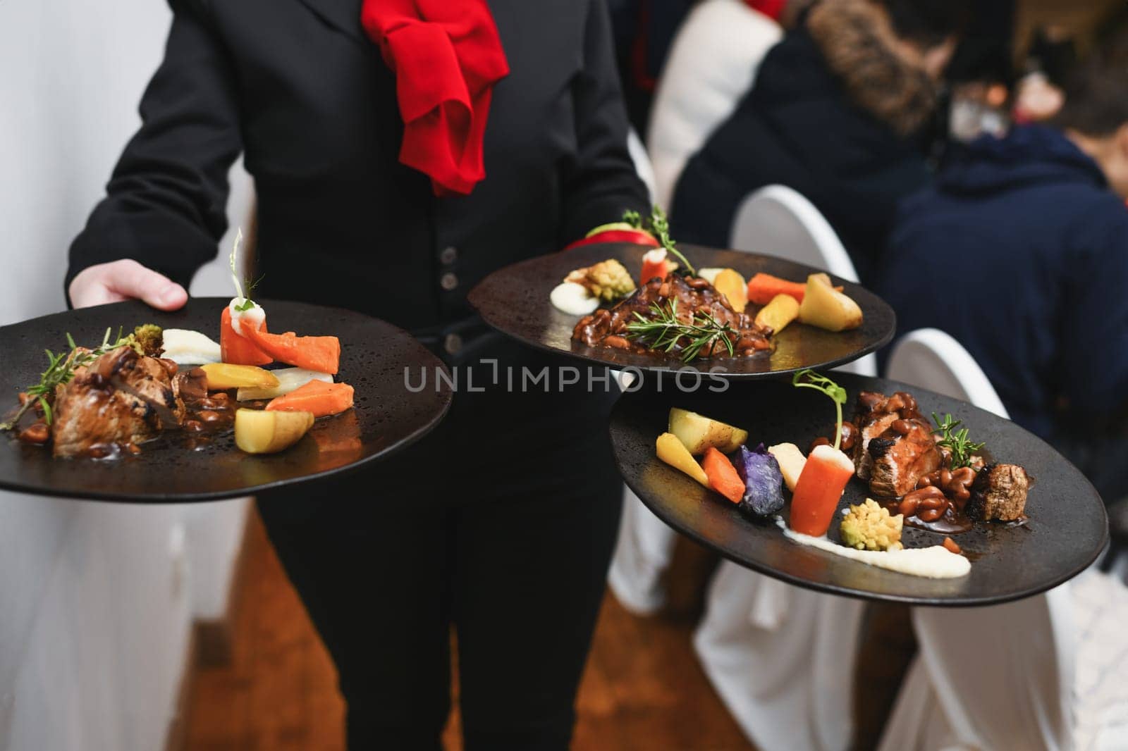 Waiter serving meat with vegetables in restaurant