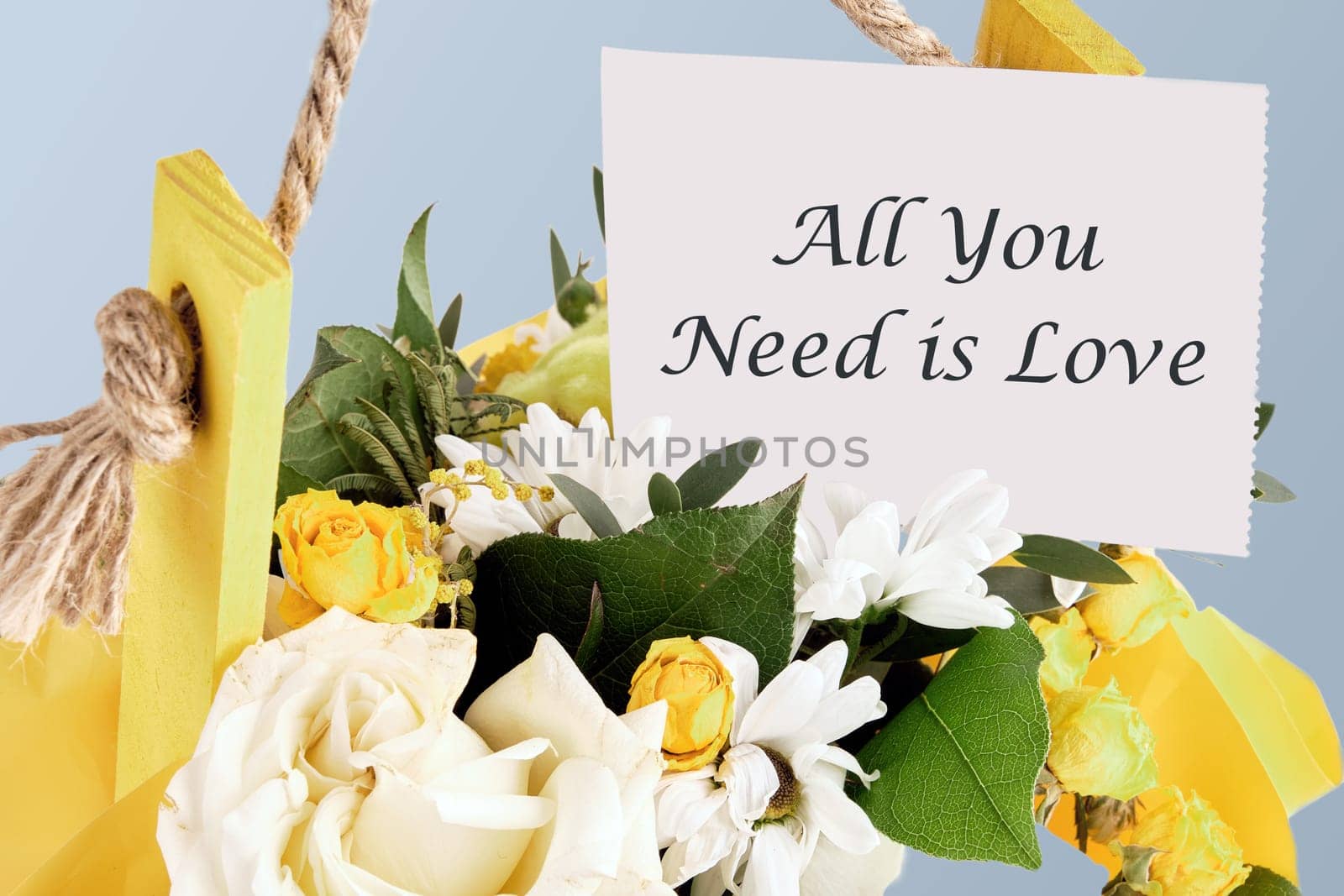 All you need is love slogan written on paper in a basket with flowers.The concept of gifts and celebrations