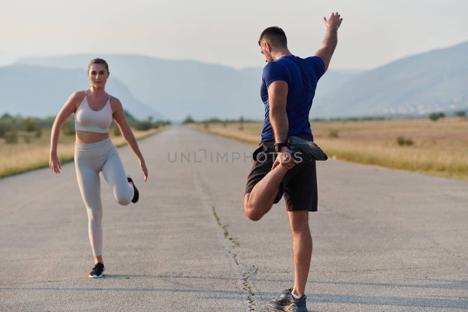 A determined group of athletes engage in a collective stretching session before their run, fostering teamwork and preparation in pursuit of their fitness goals.