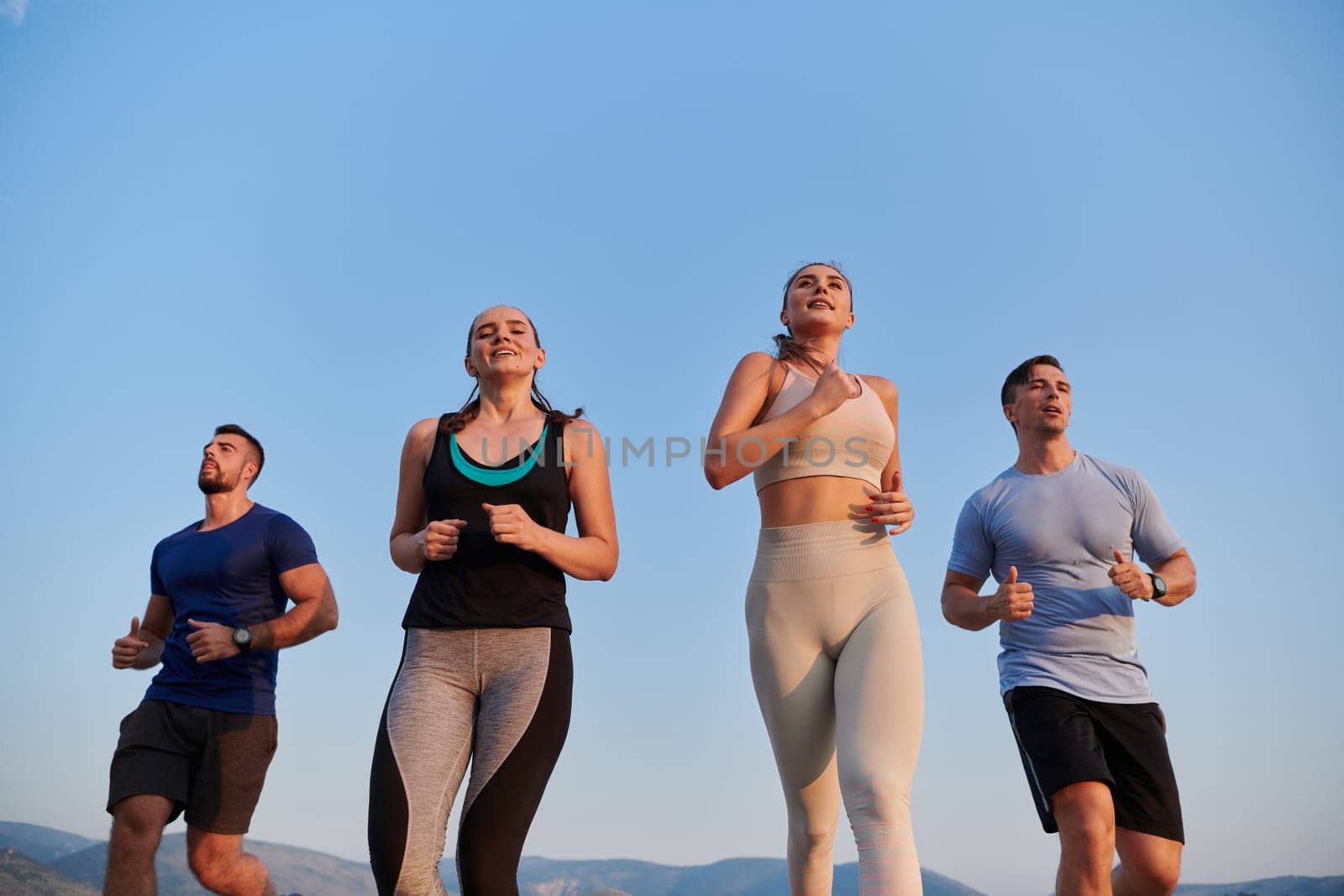 A group of friends maintains a healthy lifestyle by running outdoors on a sunny day, bonding over fitness and enjoying the energizing effects of exercise and nature by dotshock