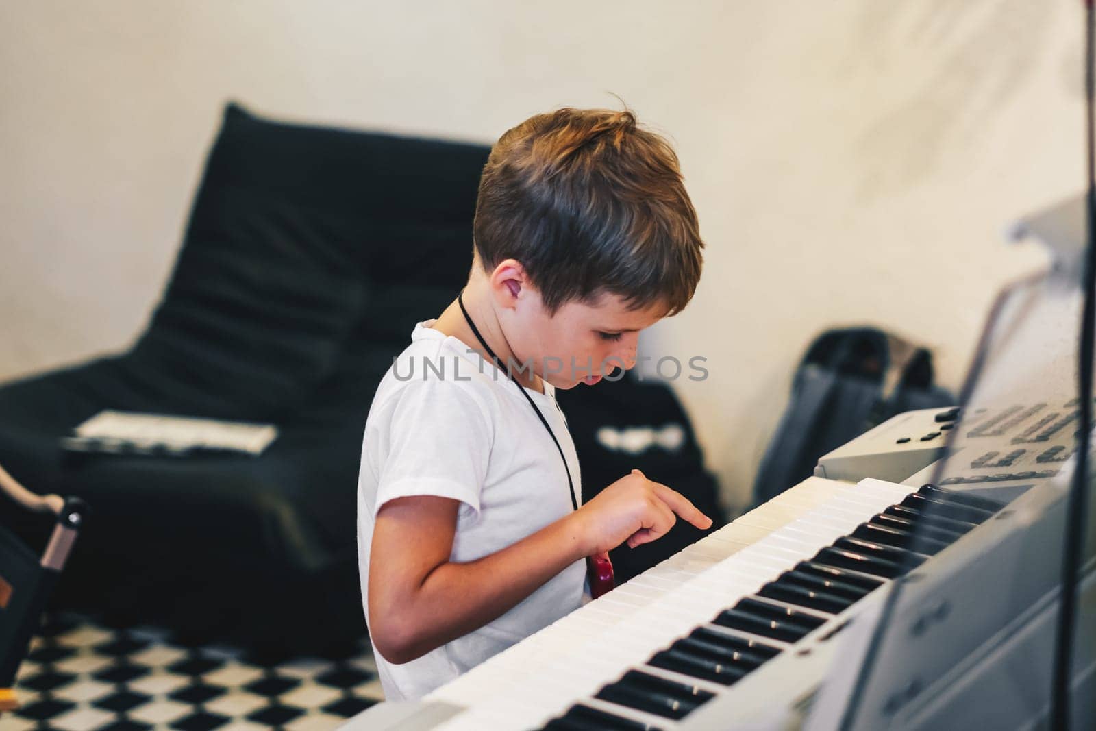 Young boy Portrait sitting at digital piano Playing keyboard focused kid activity indoors press on Key learning to play music room Hobby.