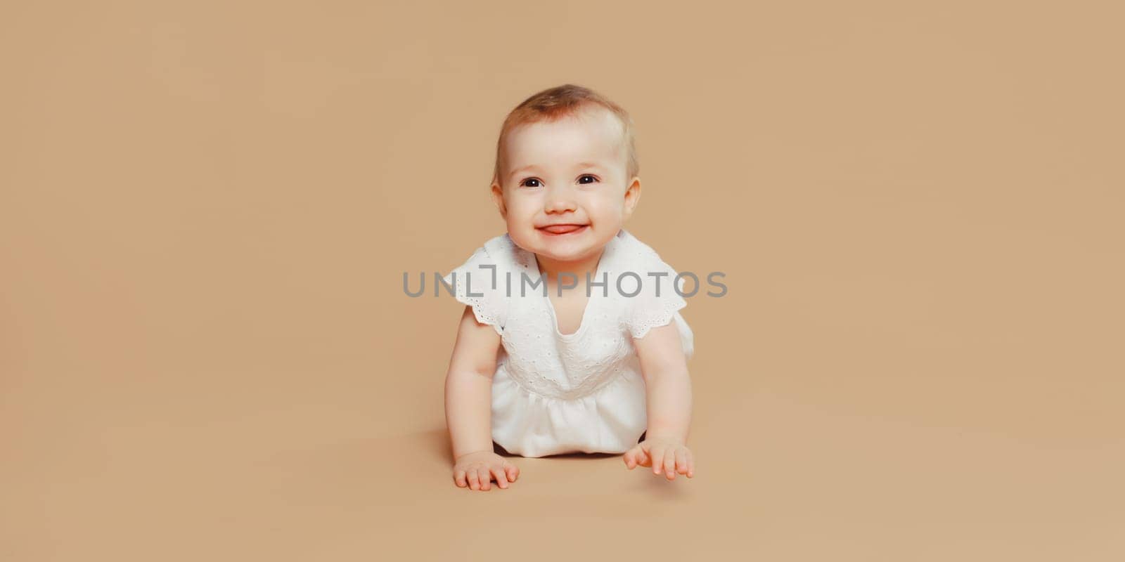 Happy cute baby crawling on the floor on brown studio background by Rohappy