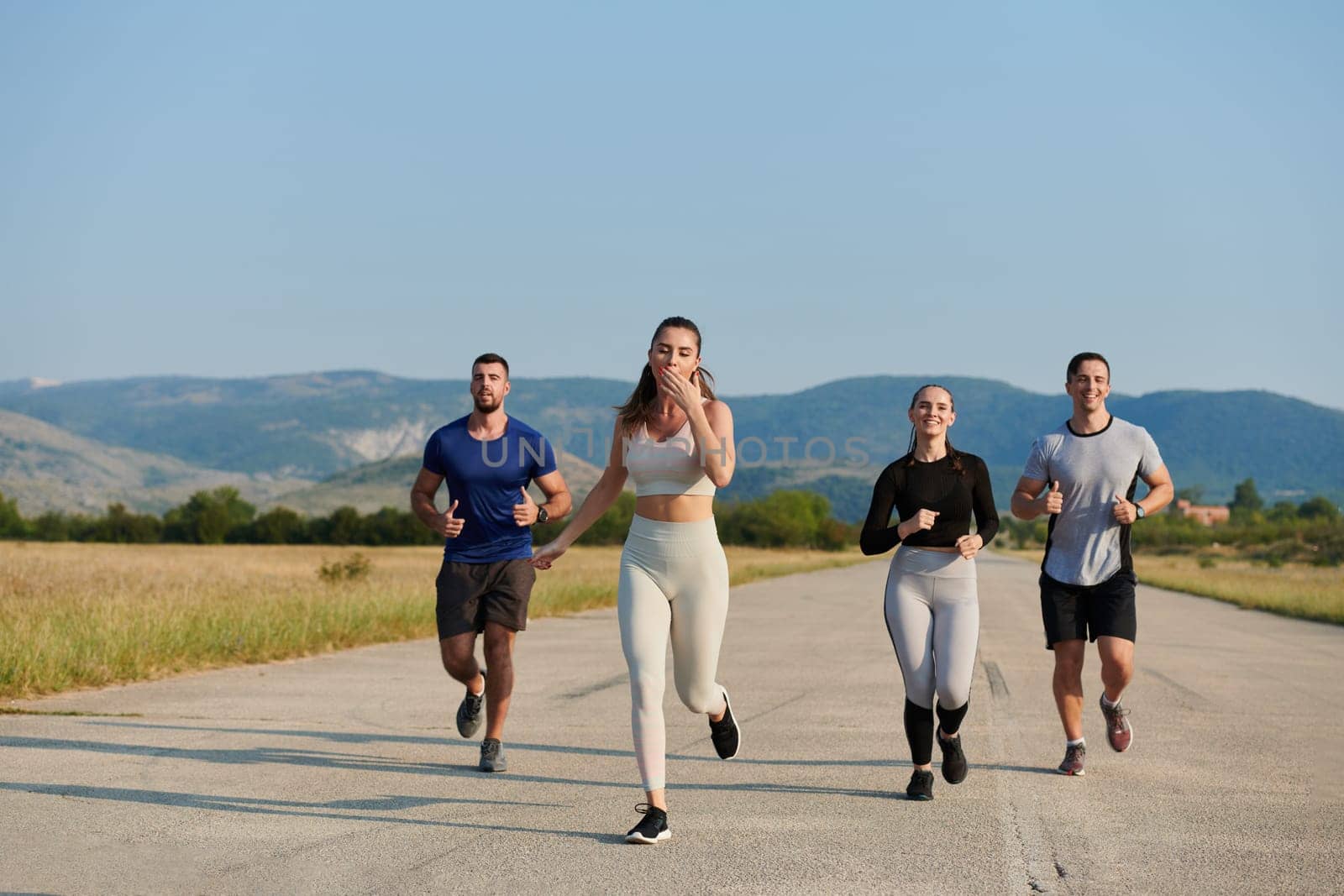 A group of friends maintains a healthy lifestyle by running outdoors on a sunny day, bonding over fitness and enjoying the energizing effects of exercise and nature.