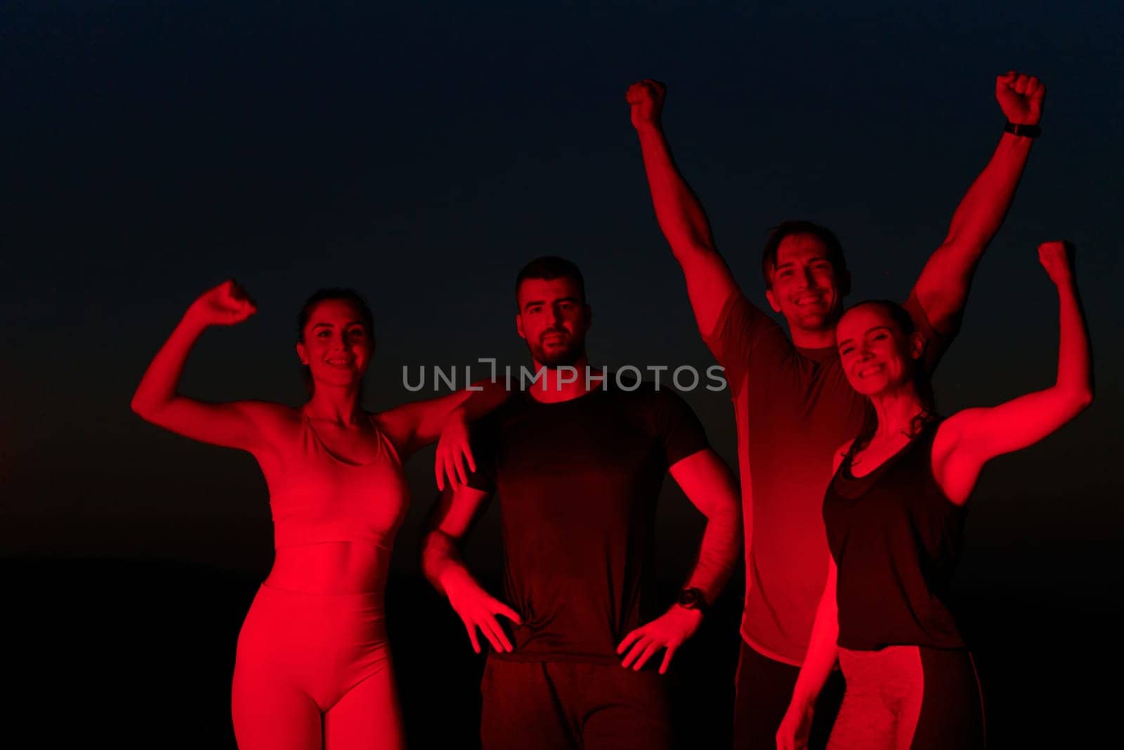 In the late hours of the night, a jubilant group of friends celebrates with cheers and embraces, reveling in the shared success of completing a long marathon.