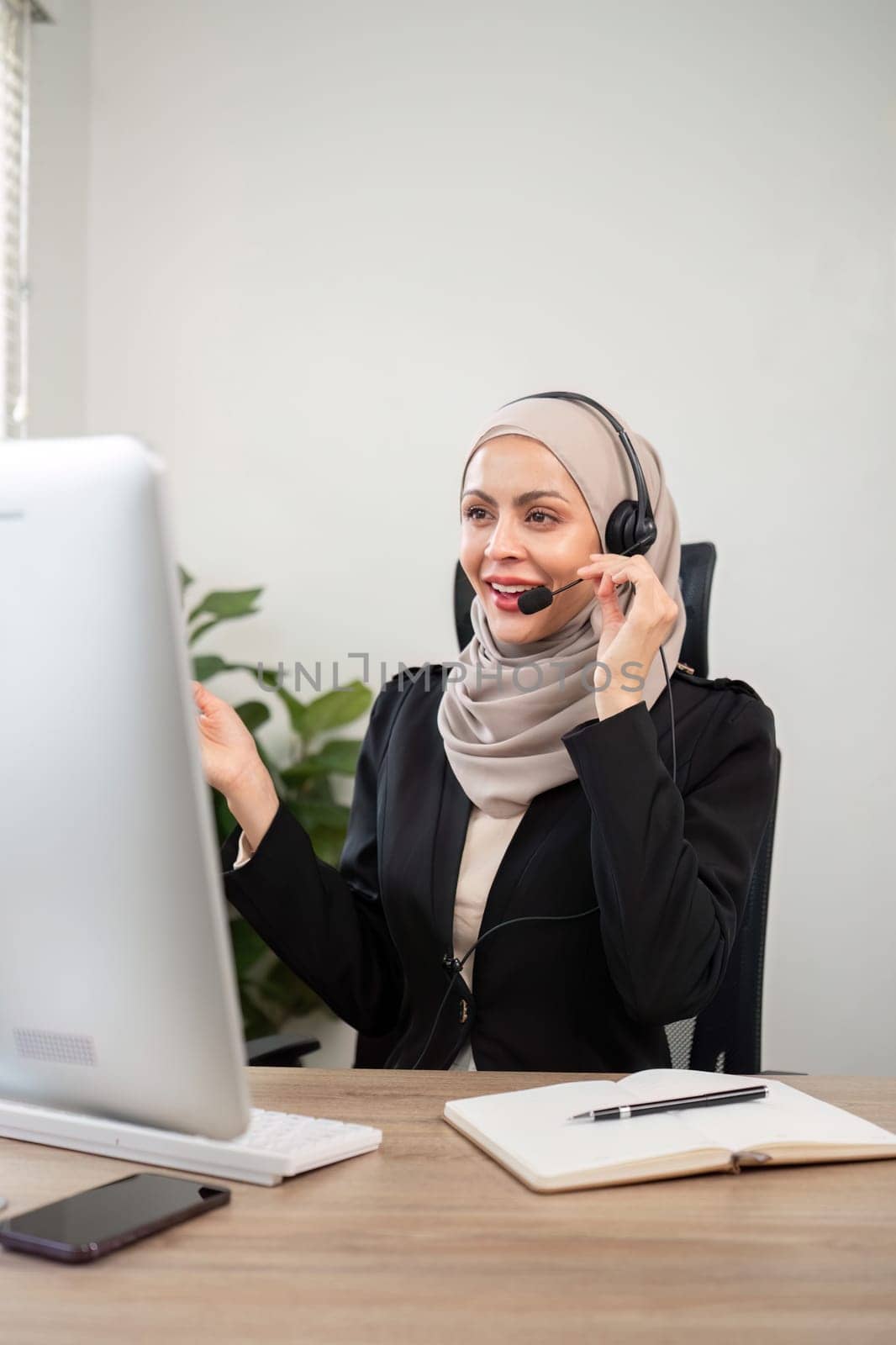 Young muslim women wearing hijab telemarketing or call center agent with headset working on support hotline at office by nateemee