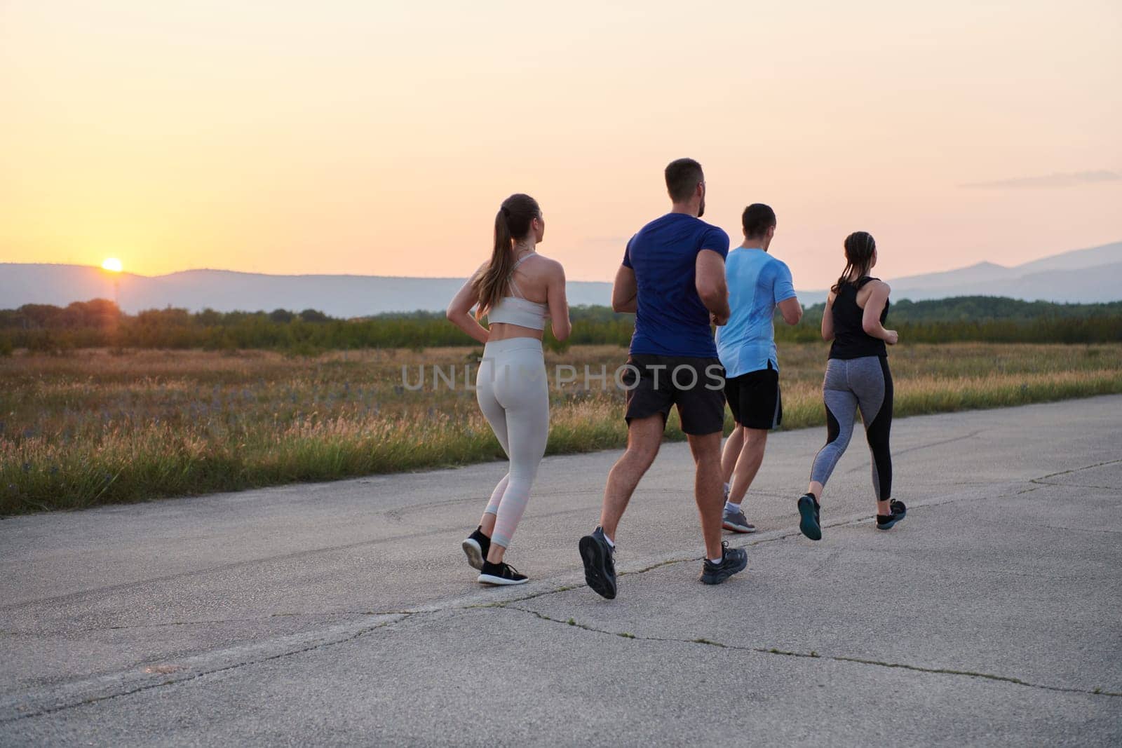 A diverse group of runners trains together at sunset. by dotshock