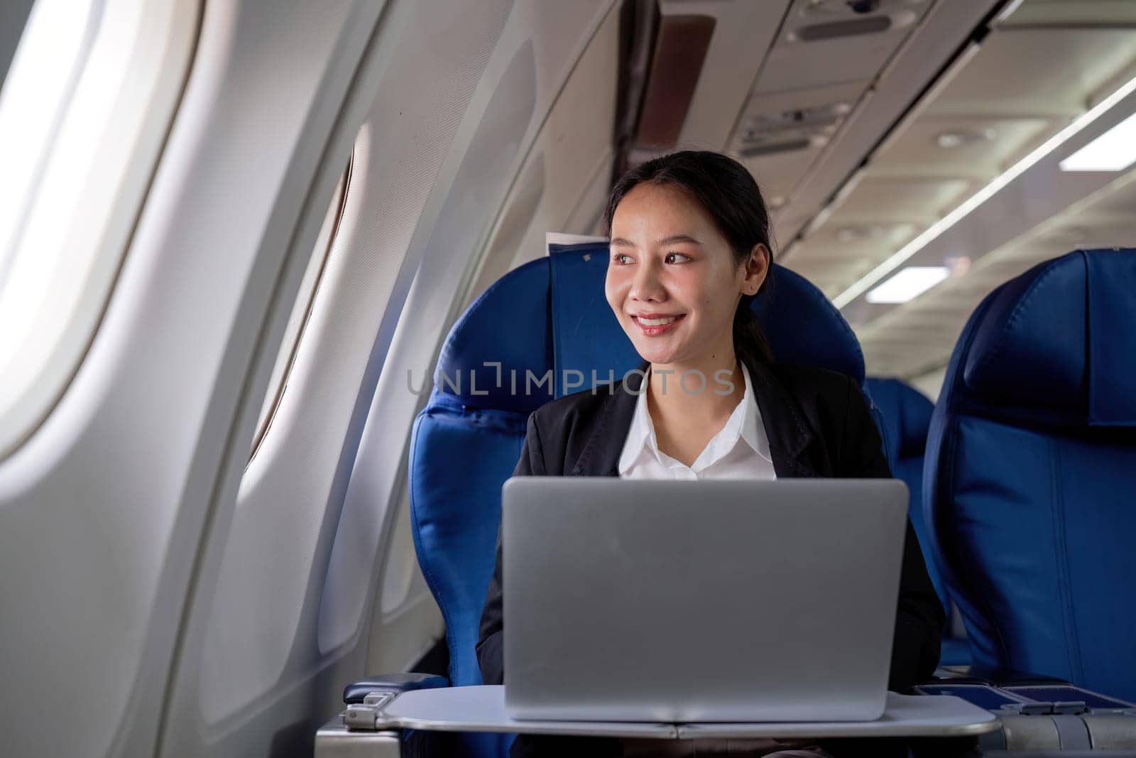 A young business woman travels to work outside the city by flying in business class. and work on airplanes with laptops by wichayada