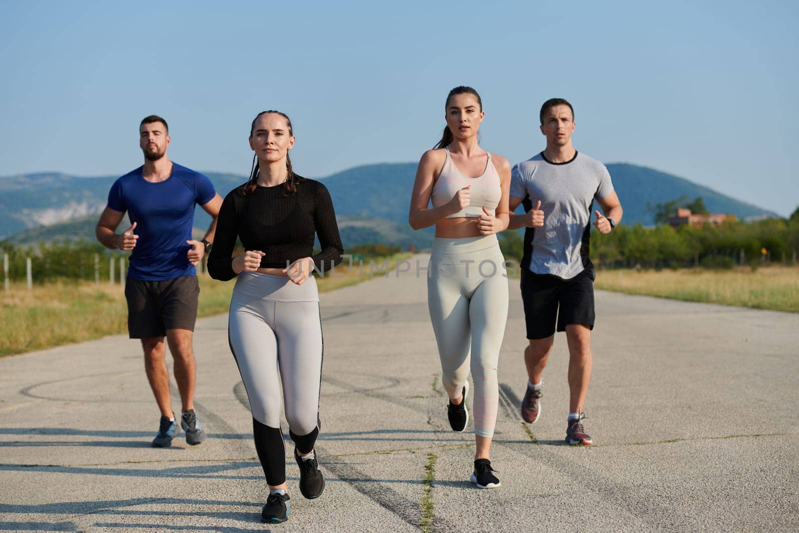 A group of friends maintains a healthy lifestyle by running outdoors on a sunny day, bonding over fitness and enjoying the energizing effects of exercise and nature.