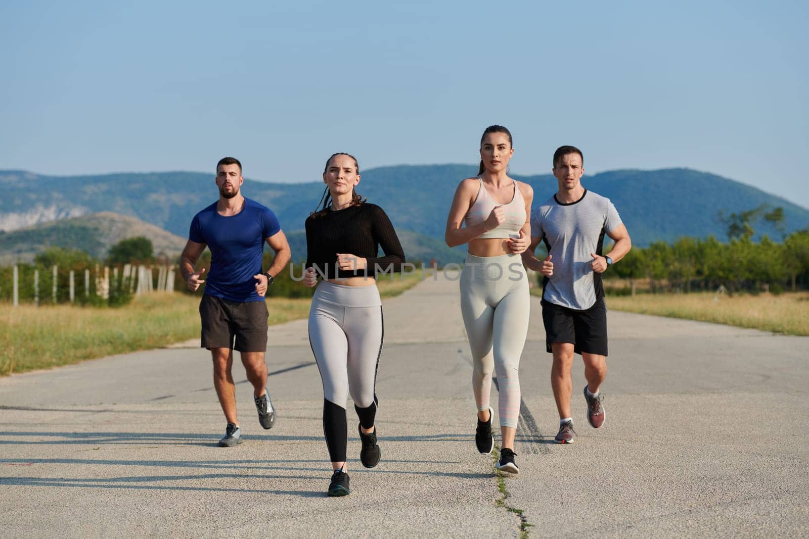 A group of friends maintains a healthy lifestyle by running outdoors on a sunny day, bonding over fitness and enjoying the energizing effects of exercise and nature by dotshock