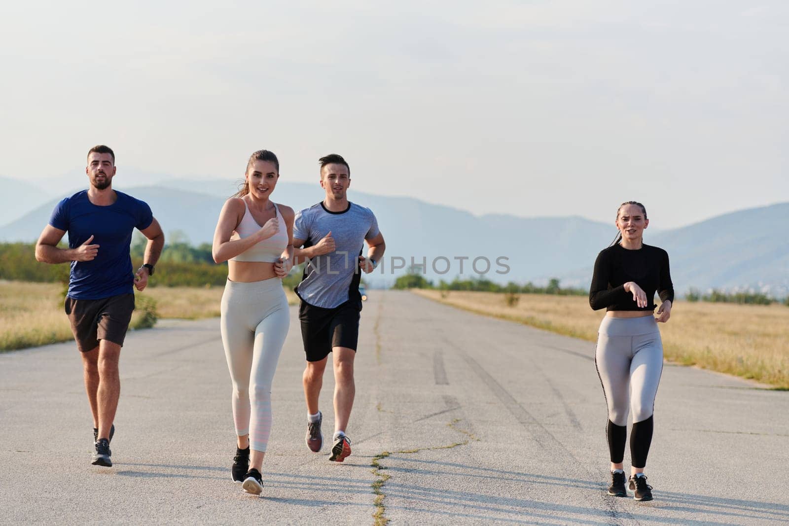 A group of friends maintains a healthy lifestyle by running outdoors on a sunny day, bonding over fitness and enjoying the energizing effects of exercise and nature by dotshock