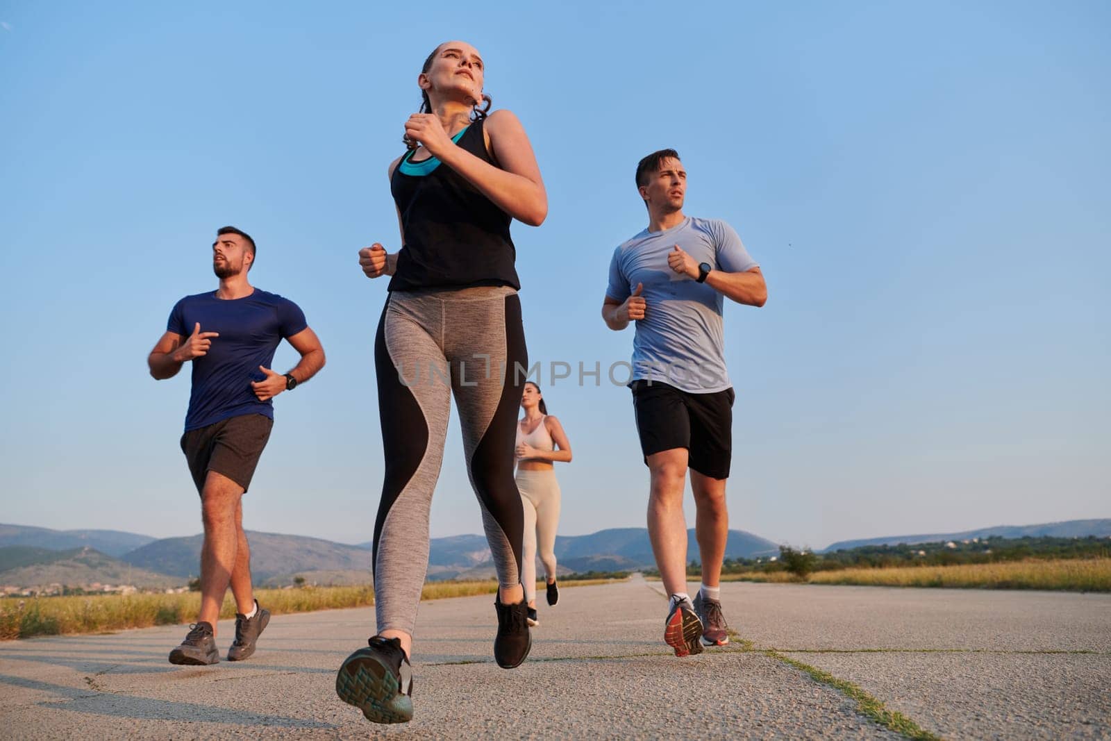 A group of friends maintains a healthy lifestyle by running outdoors on a sunny day, bonding over fitness and enjoying the energizing effects of exercise and nature.