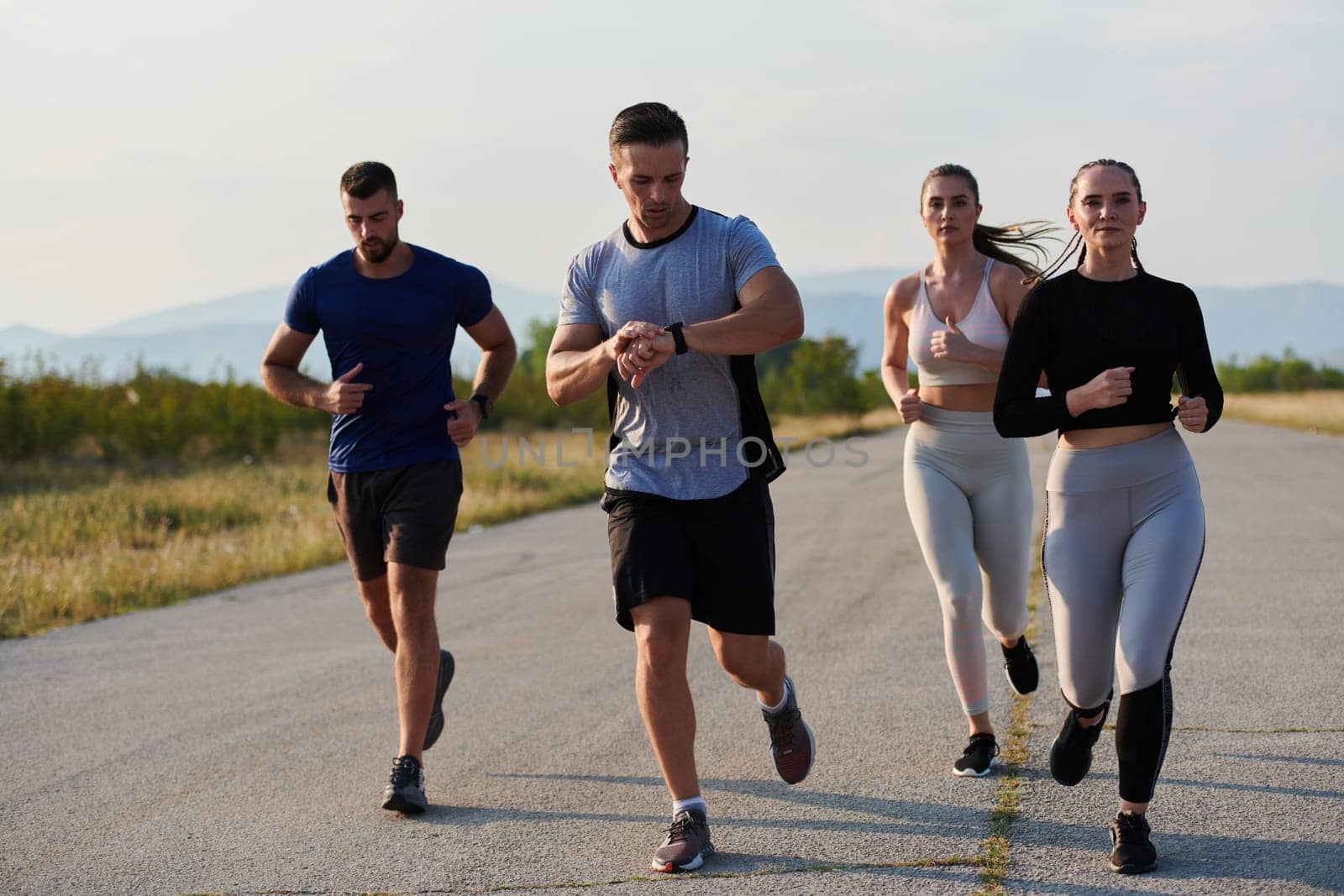 A group of friends maintains a healthy lifestyle by running outdoors on a sunny day, bonding over fitness and enjoying the energizing effects of exercise and nature by dotshock