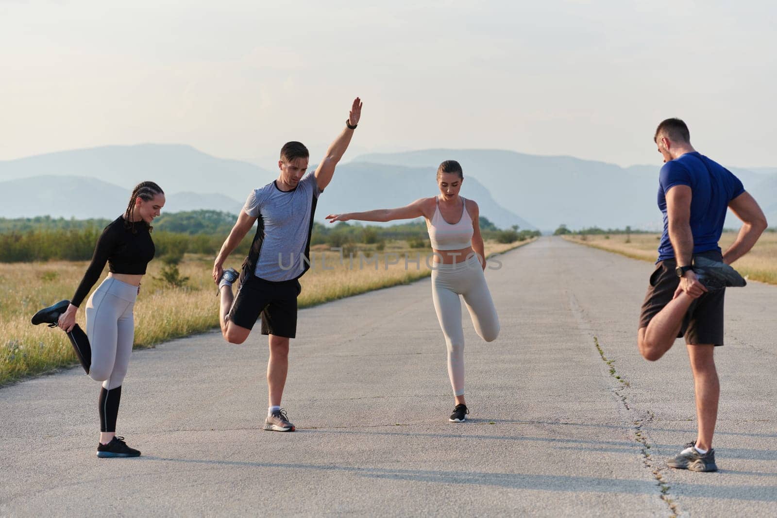 A determined group of athletes engage in a collective stretching session before their run, fostering teamwork and preparation in pursuit of their fitness goals.