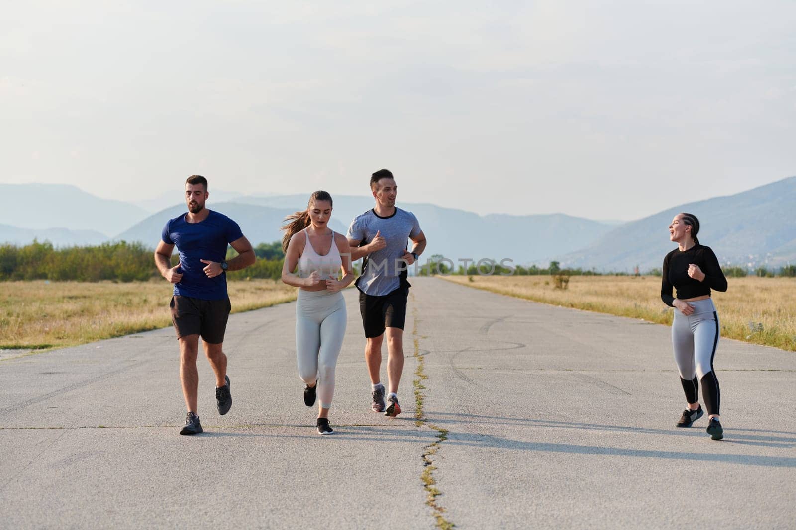 A group of friends maintains a healthy lifestyle by running outdoors on a sunny day, bonding over fitness and enjoying the energizing effects of exercise and nature by dotshock