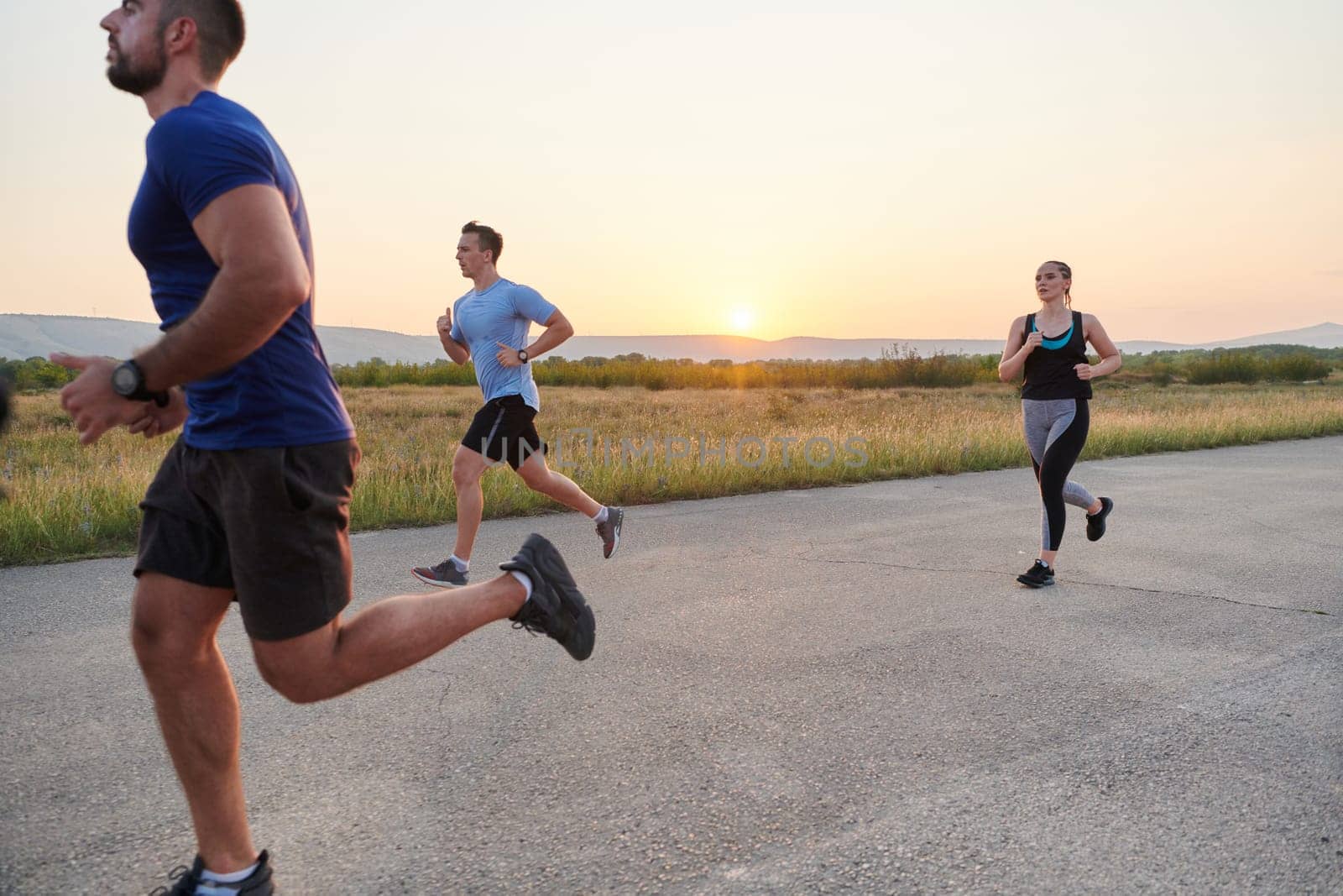 A diverse group of runners finds motivation and inspiration in each other as they train together for an upcoming competition, set against a breathtaking sunset backdrop.