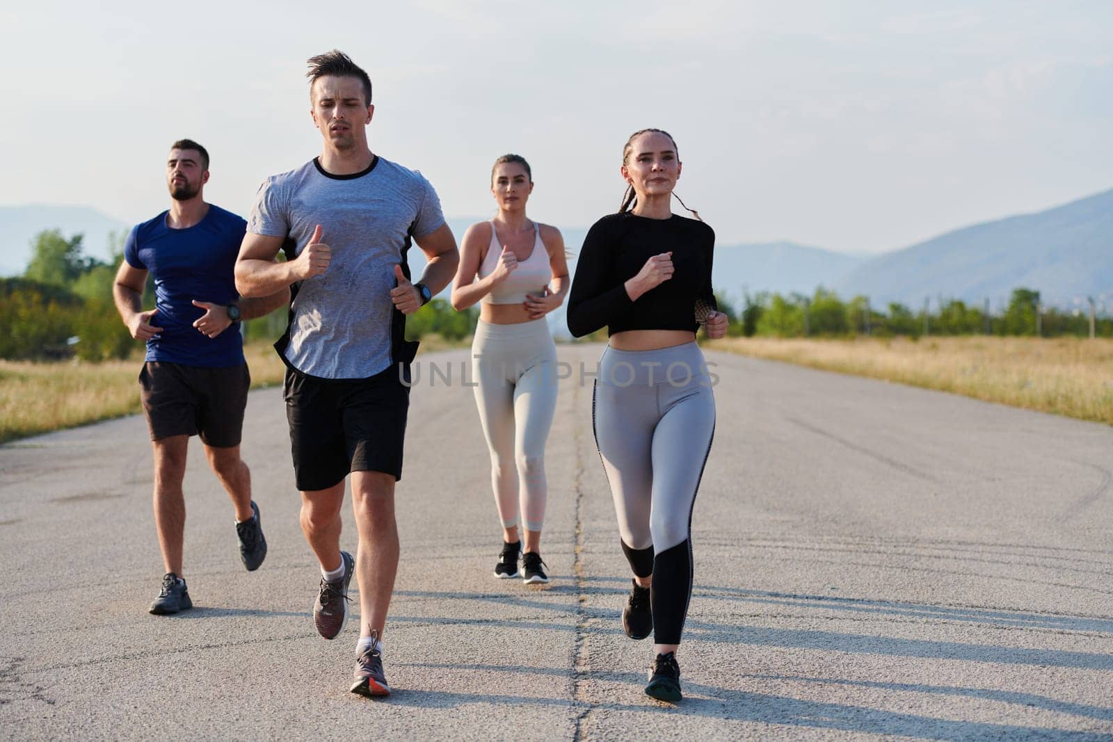 A group of friends maintains a healthy lifestyle by running outdoors on a sunny day, bonding over fitness and enjoying the energizing effects of exercise and nature by dotshock