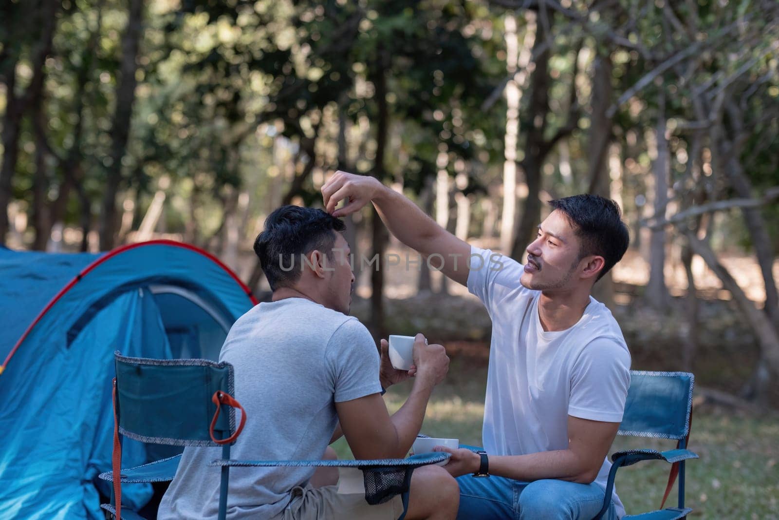 Young Asian homosexual couple spending their free time Holidays sitting together, relaxing, camping and hiking together. by wichayada