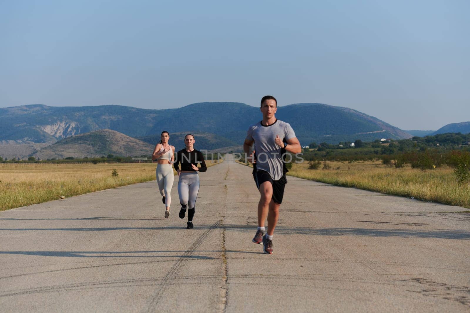 A group of friends maintains a healthy lifestyle by running outdoors on a sunny day, bonding over fitness and enjoying the energizing effects of exercise and nature.