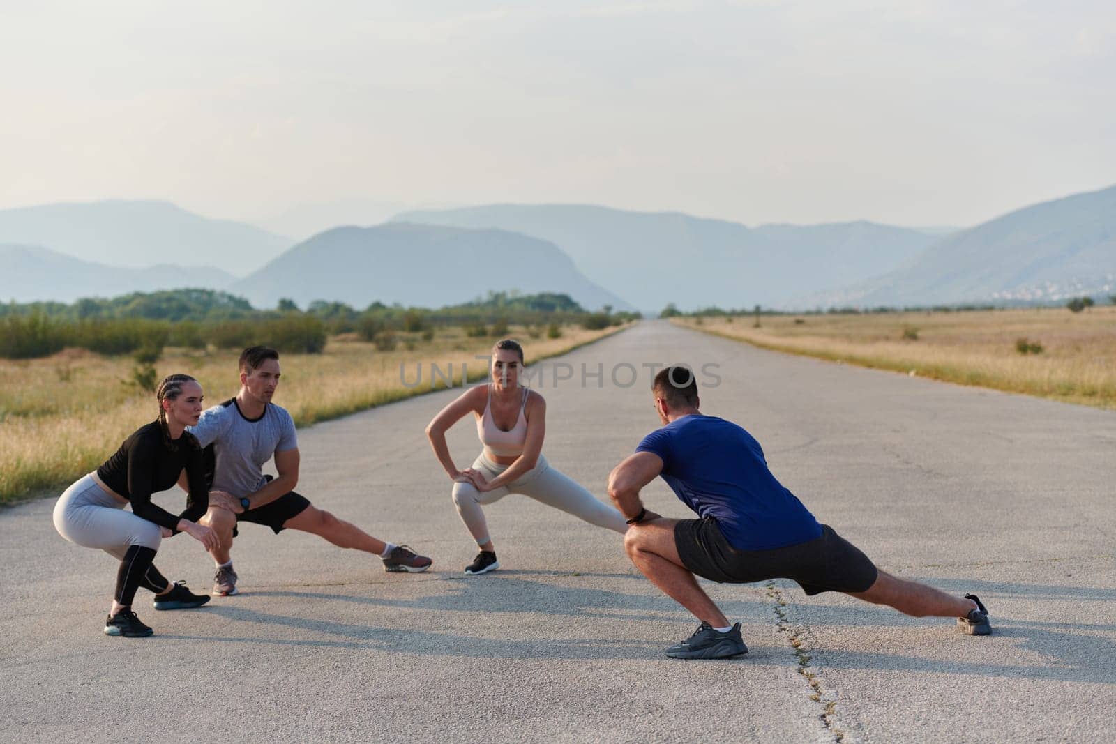 A determined group of athletes engage in a collective stretching session before their run, fostering teamwork and preparation in pursuit of their fitness goals.