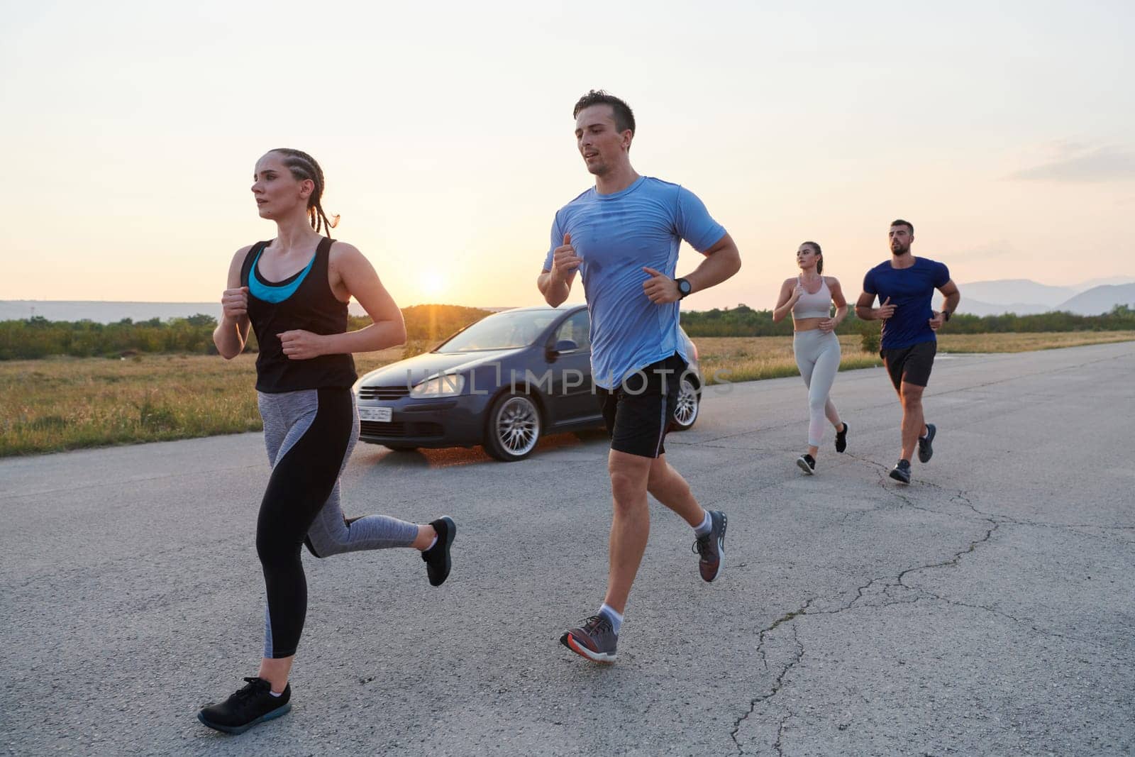 A diverse group of runners trains together at sunset. by dotshock