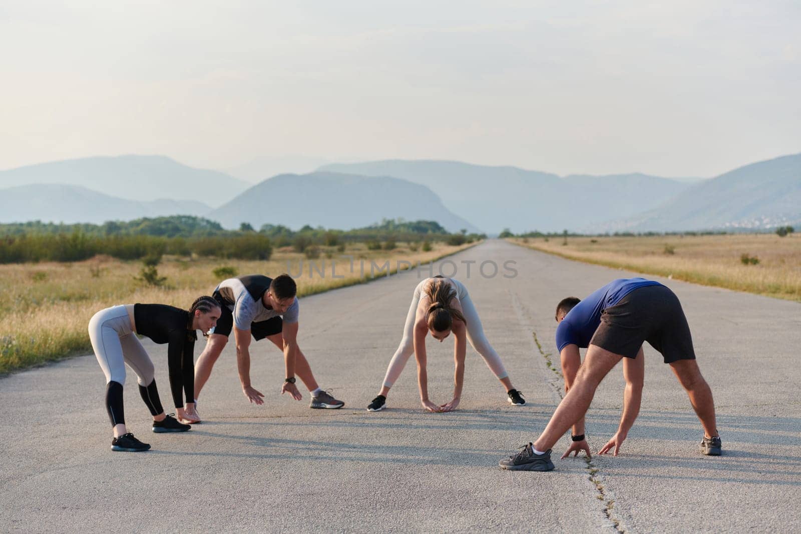 A determined group of athletes engage in a collective stretching session before their run, fostering teamwork and preparation in pursuit of their fitness goals.