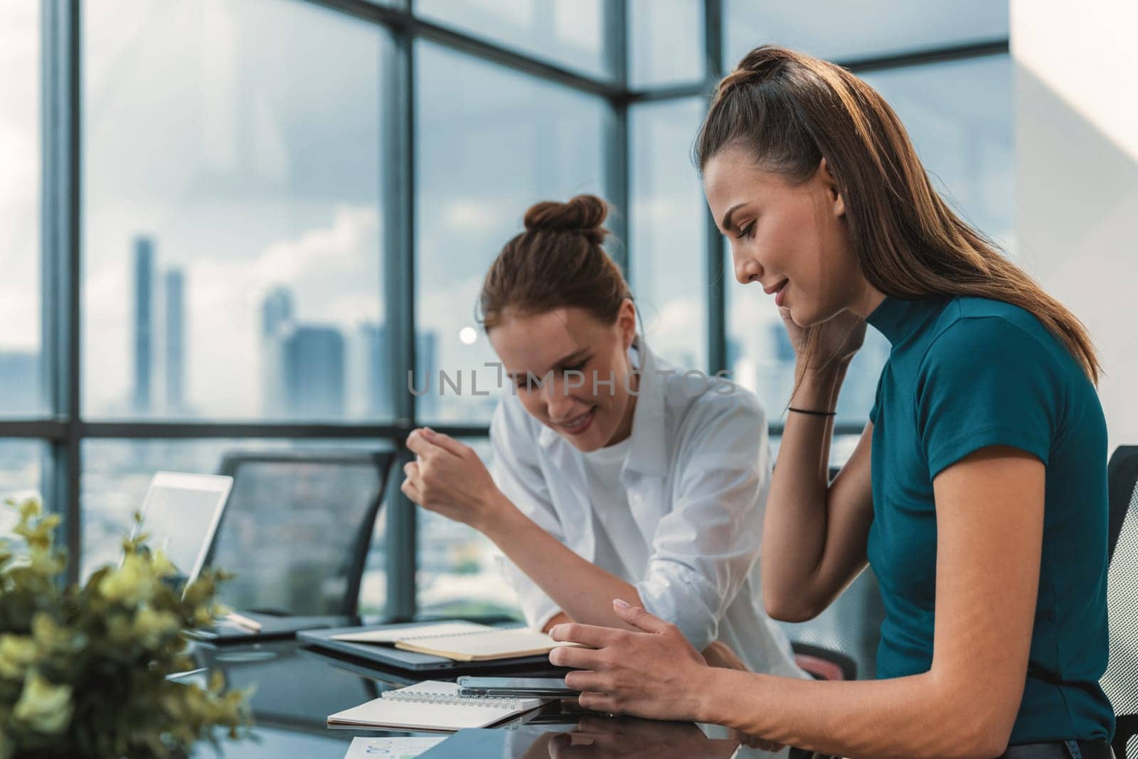 Portrait of two young beautiful caucasian businesswoman using phone while meeting to sharing searching brainstorming marketing idea. Group of businesswoman working together. Corporate. Tracery.