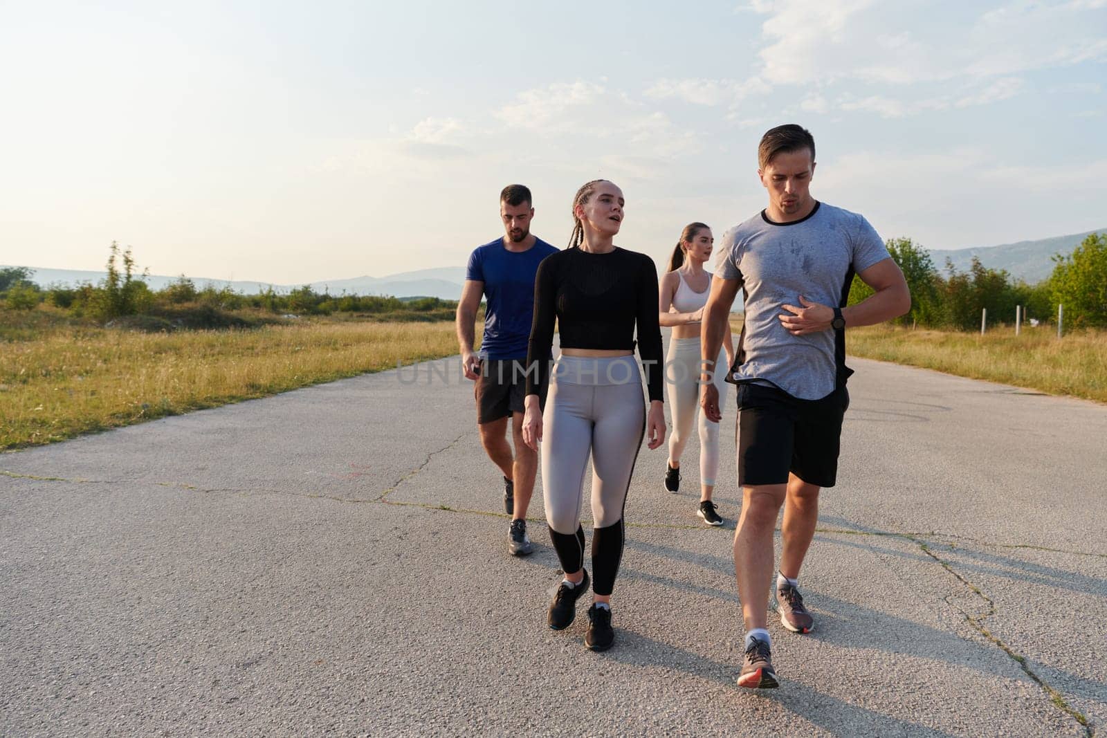 A group of friends maintains a healthy lifestyle by running outdoors on a sunny day, bonding over fitness and enjoying the energizing effects of exercise and nature.