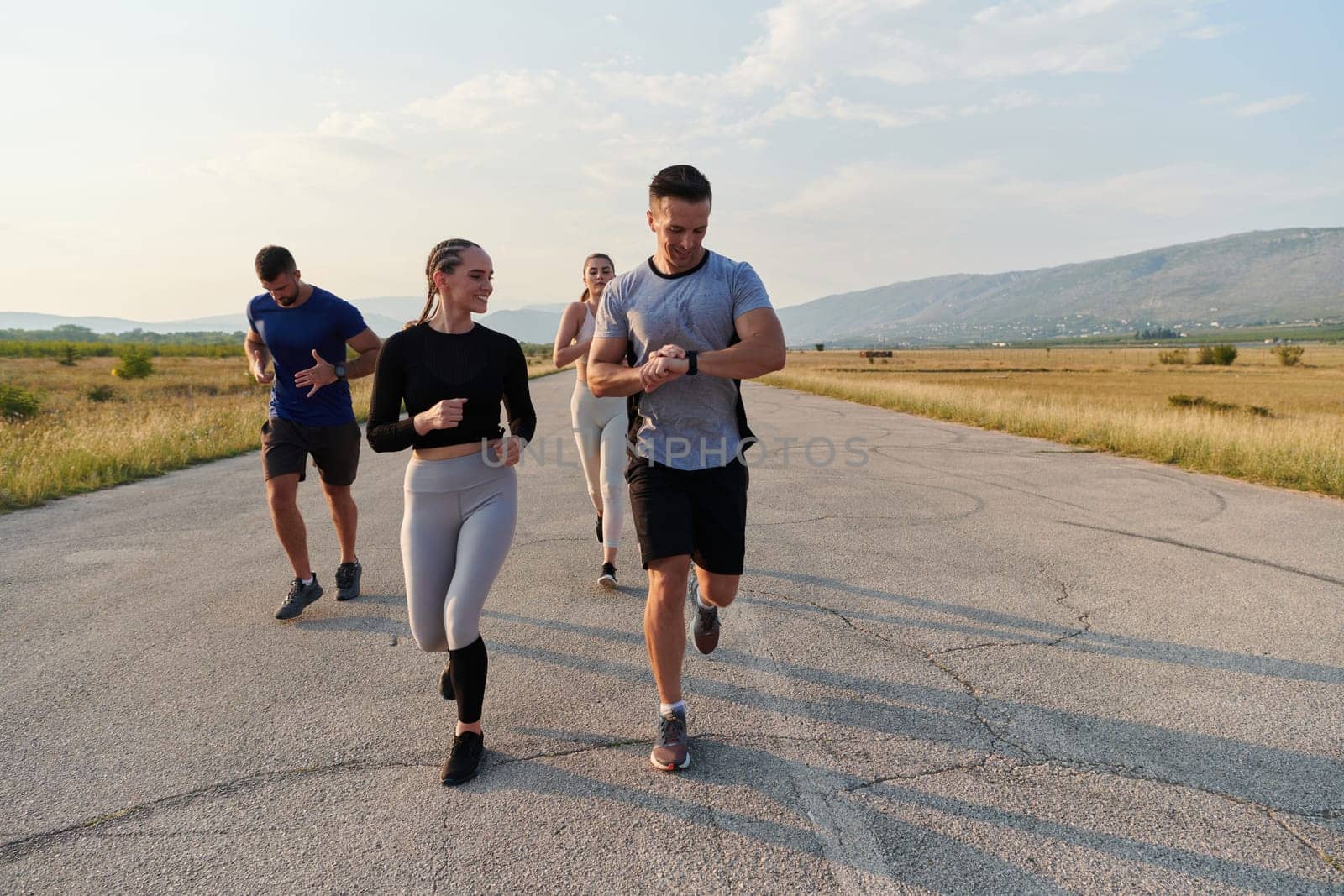 A group of friends maintains a healthy lifestyle by running outdoors on a sunny day, bonding over fitness and enjoying the energizing effects of exercise and nature by dotshock