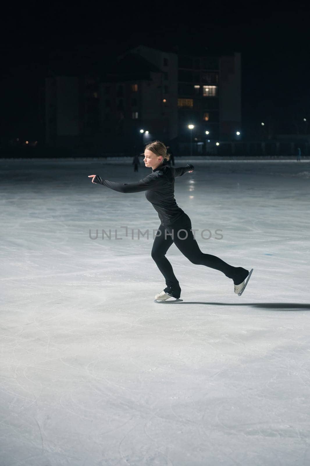 Beautiful young woman ice skating at city ice arena. Winter activities concept