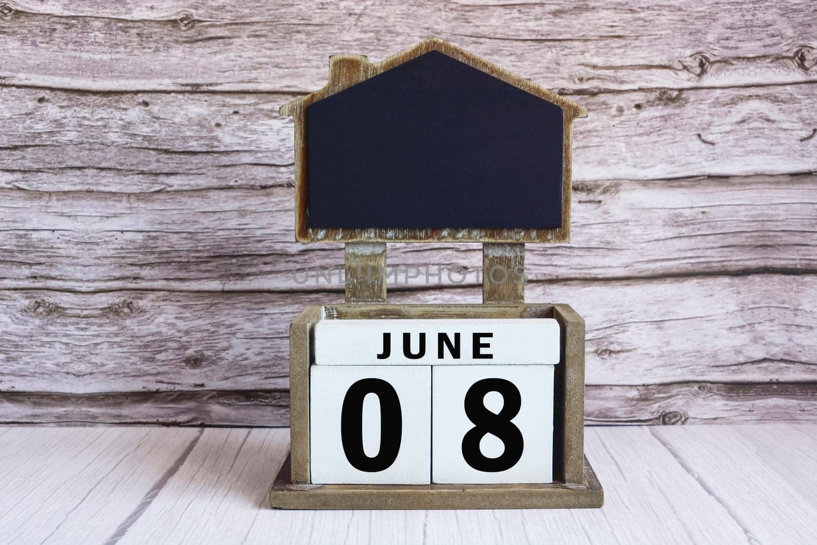 Chalkboard with June 08 date on white cube block on wooden table. by JennMiranda