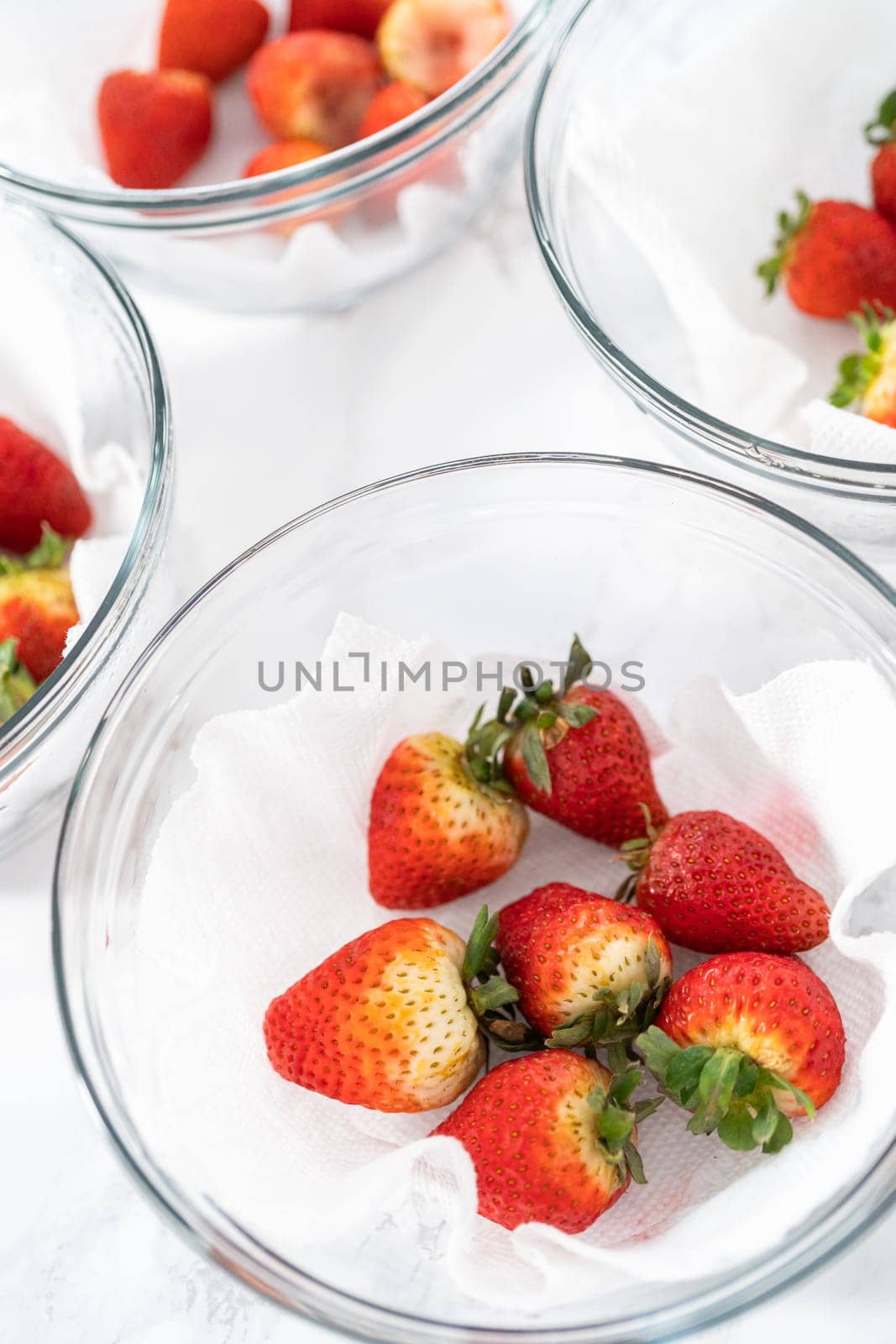 Fresh and Moldy Strawberries in a Glass Bowl on a White Napkin by arinahabich