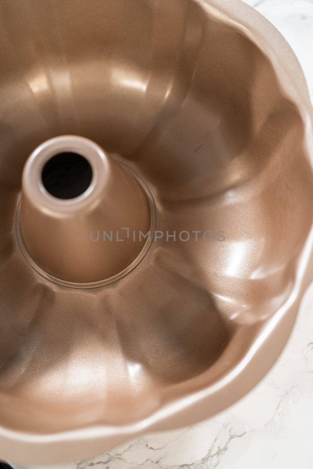 Using a silicone brush, the metal bundt cake pan is greased with melted vegetable shortening, preparing for baking the scrumptious Carrot Bundt Cake.