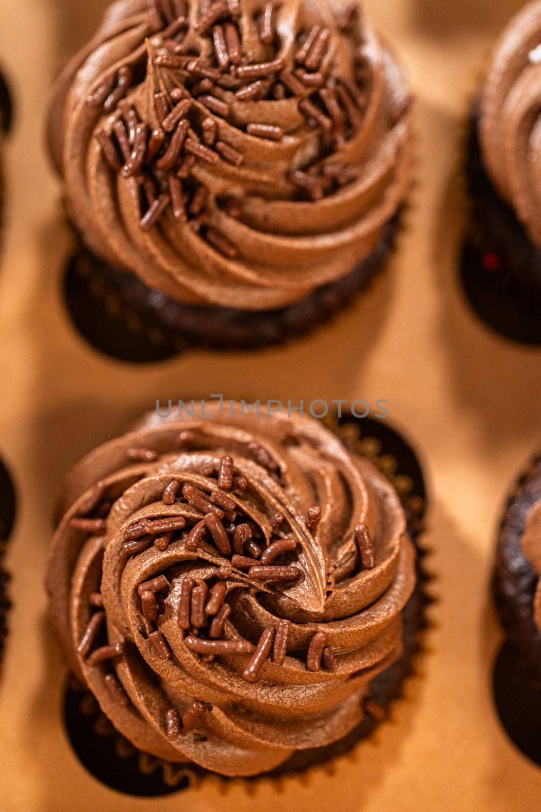 Preparing to share the delicious chocolate cupcakes, the final step involves carefully packaging them into a brown paper cupcake box.