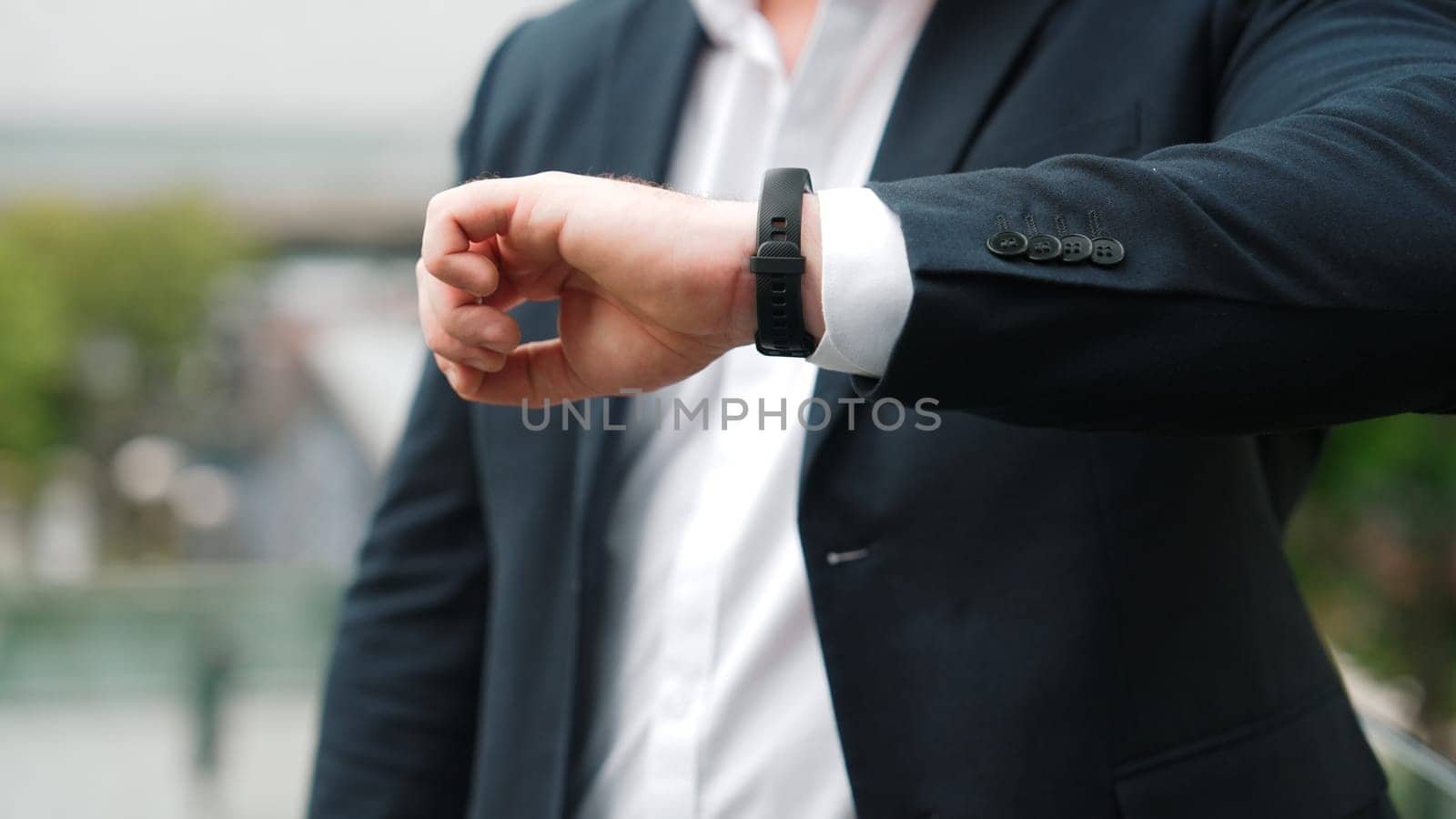 Close up of business man checking time for being on time in important appointment or meeting. Manager in a hurry while looking at watch and waiting for his teammate or colleague. Life style. Urbane.