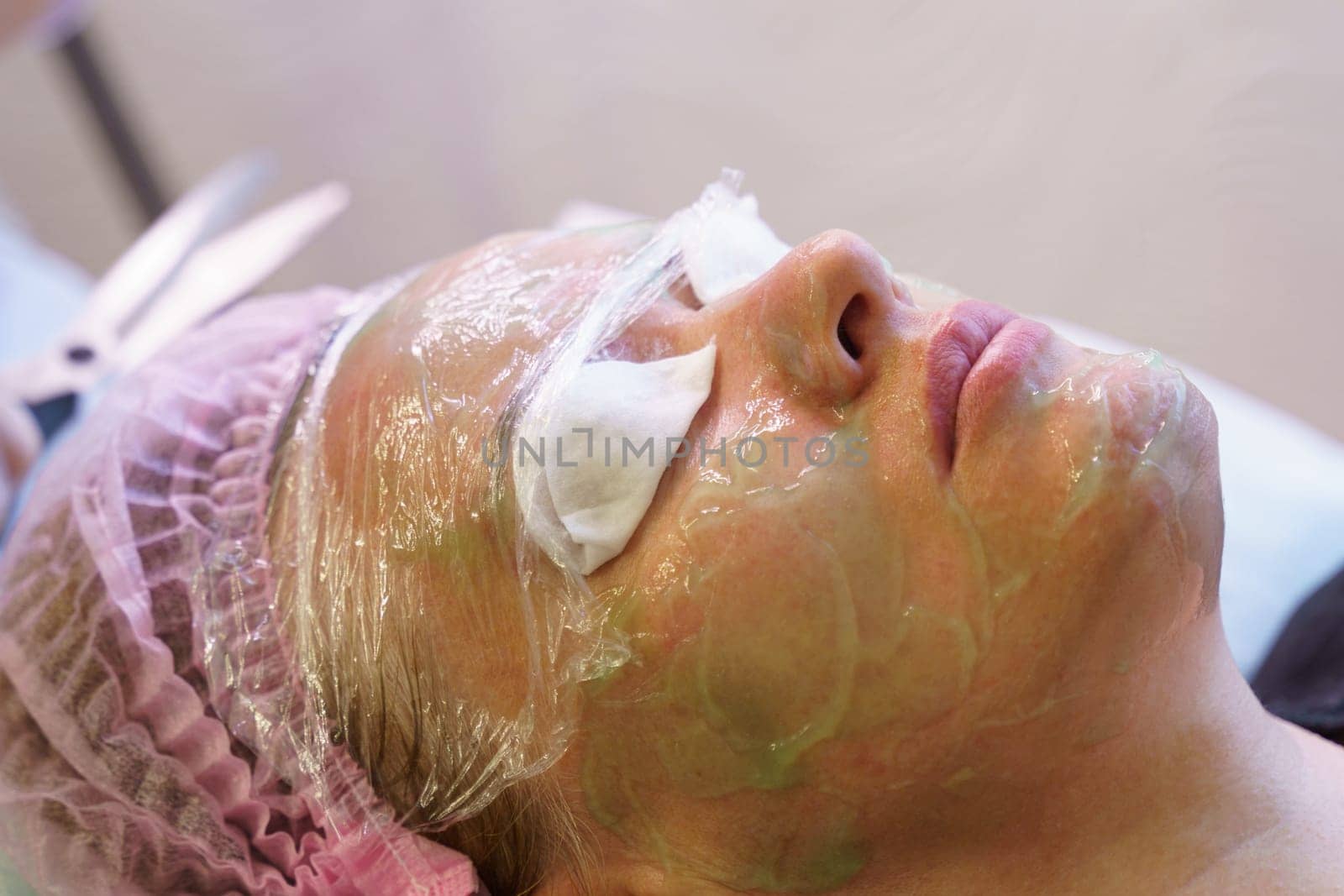 A woman having a facial mask applied to her face in a spa setting for skin rejuvenation and cleansing.