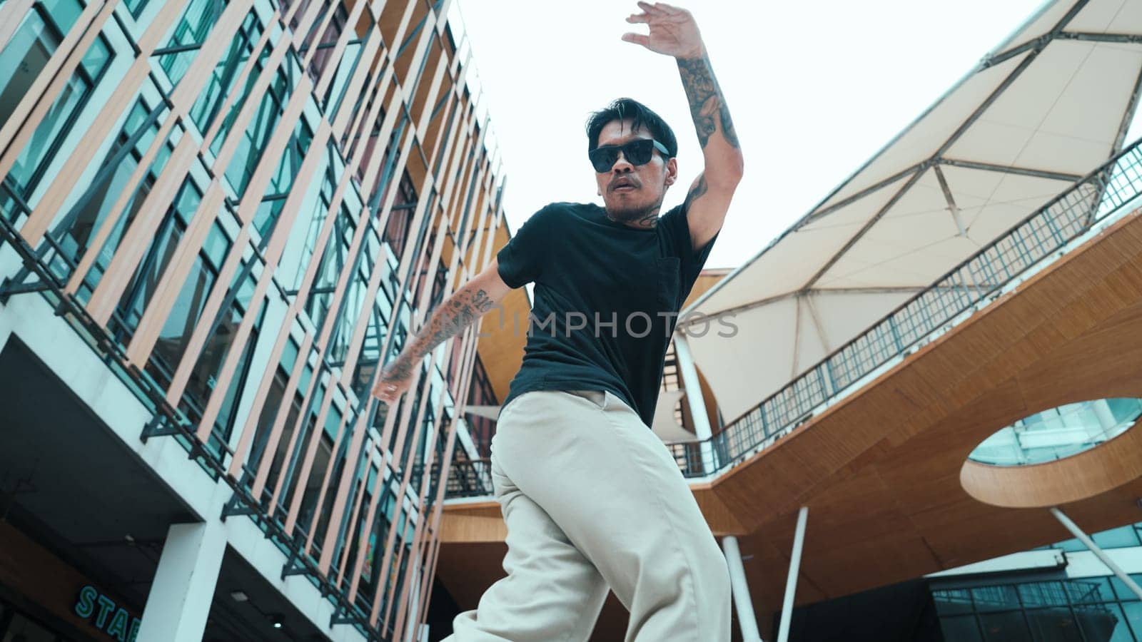 Young hispanic break dancer dance at camera with low angle camera. Portrait of enthusiasm mexican man moving by the hip hop beat or rhythm at mall. Freestyle movement. Outdoor sport 2024. Endeavor