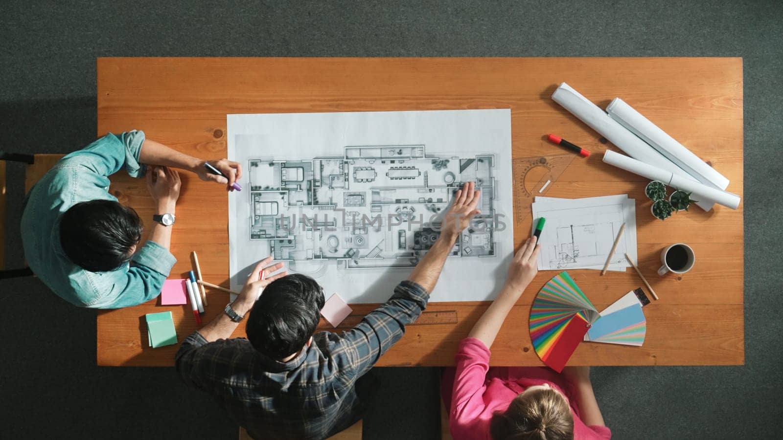 Group of people looking at blueprint while brainstorming idea. Top view of engineer team looking and planning house construction by using blueprint. Engineer hold paper while point at plan. Symposium.