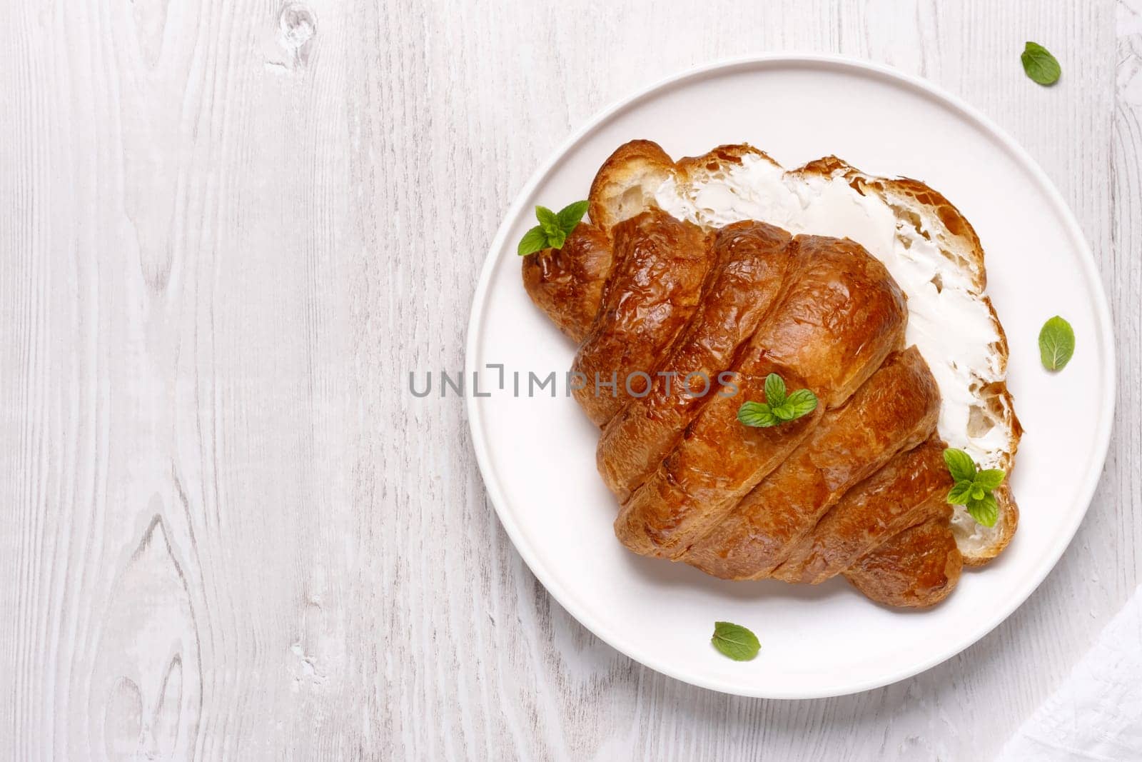Sandwich with croissant and cream cheese, decorated with mint. Healthy eating concept.