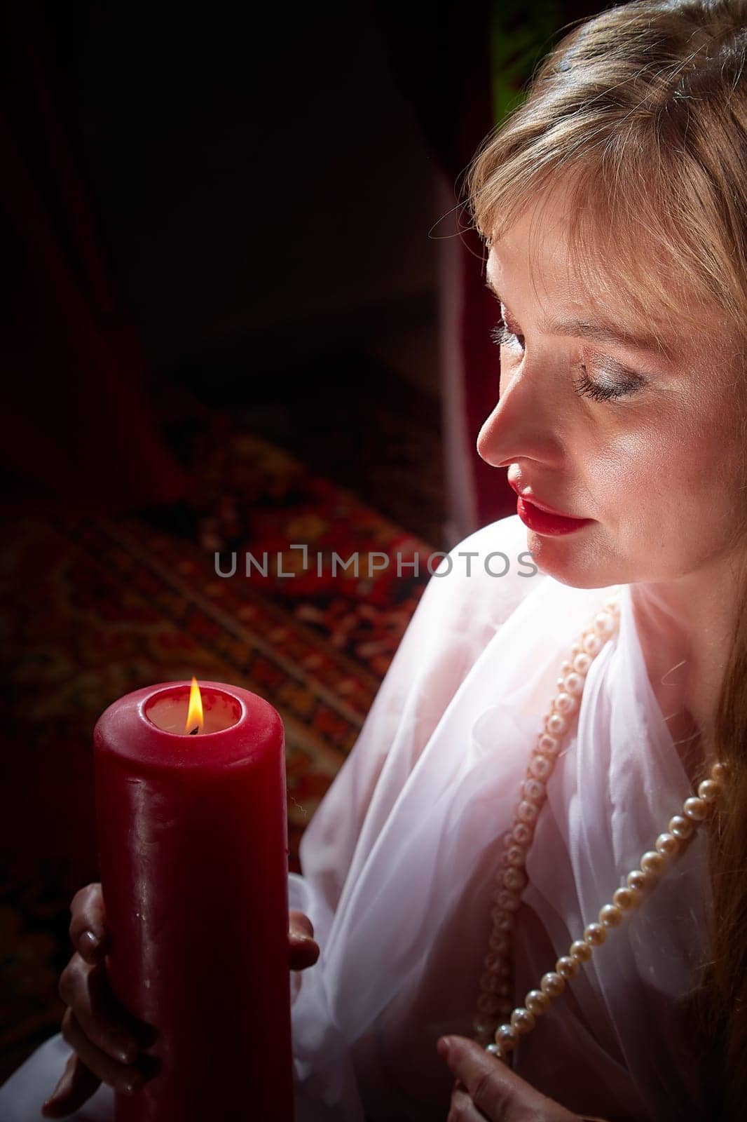 Middle aged beautiful woman holds aromatic candle in hands. Aromatherapy, meditation, healthy life concept. Peace of mind, balance, body care, healthy lifestyle by keleny