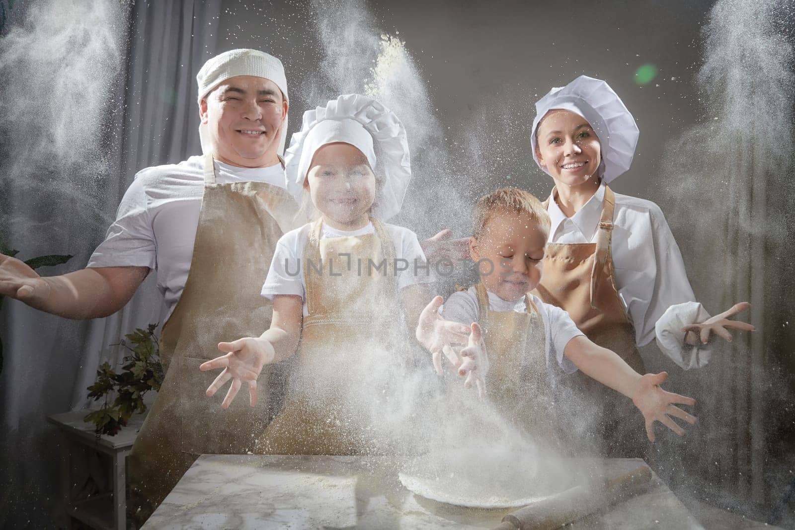 Cute oriental family with mother, father, daughter, son cooking in kitchen on Ramadan, Kurban-Bairam. Funny family at photo shoot. Easter