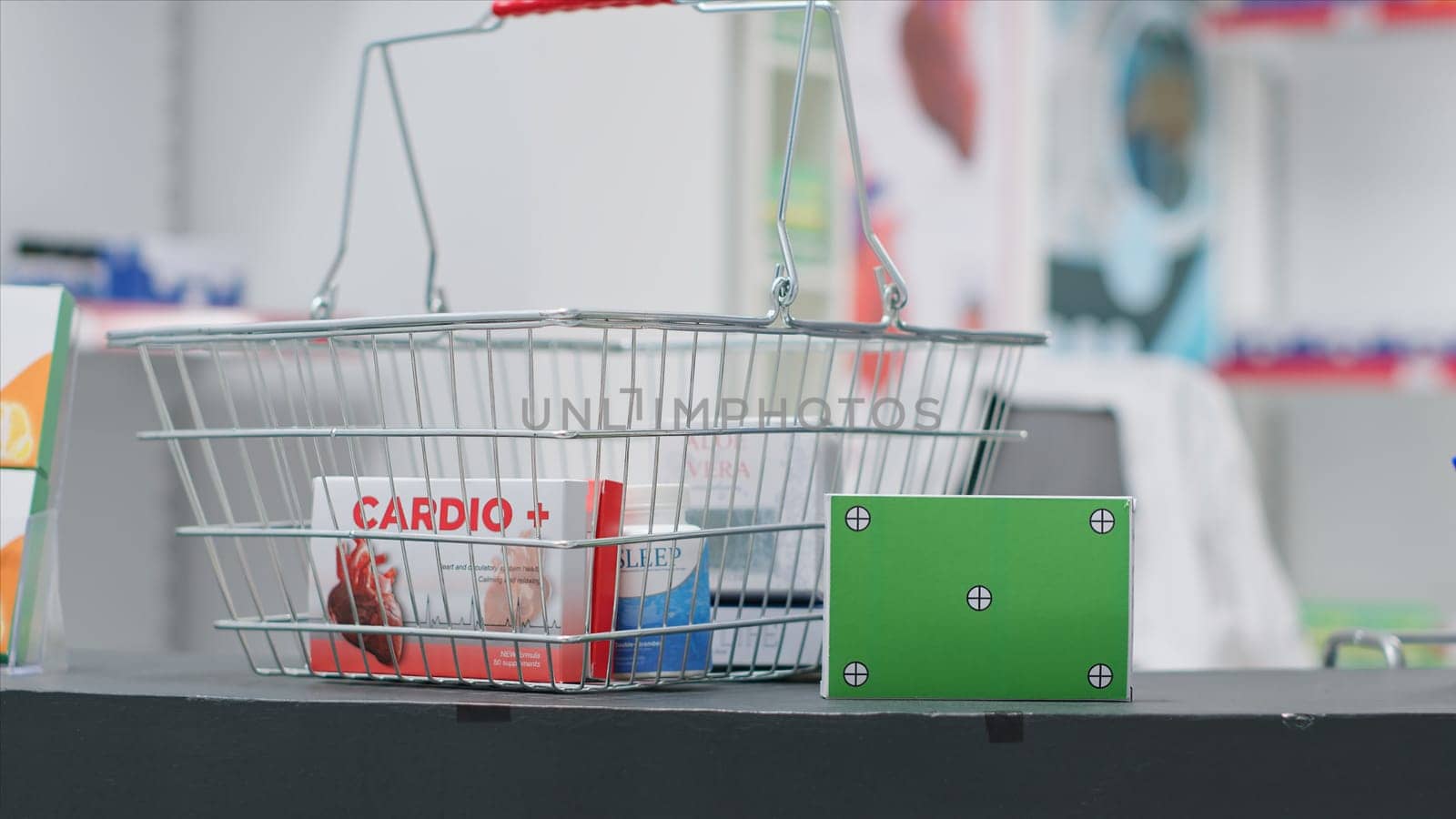 Basket filled with medicaments and a box with greenscreen layout at pharmacy cash register counter. Empty drugstore having pharmaceutics and package with isolated copyspace mockup.