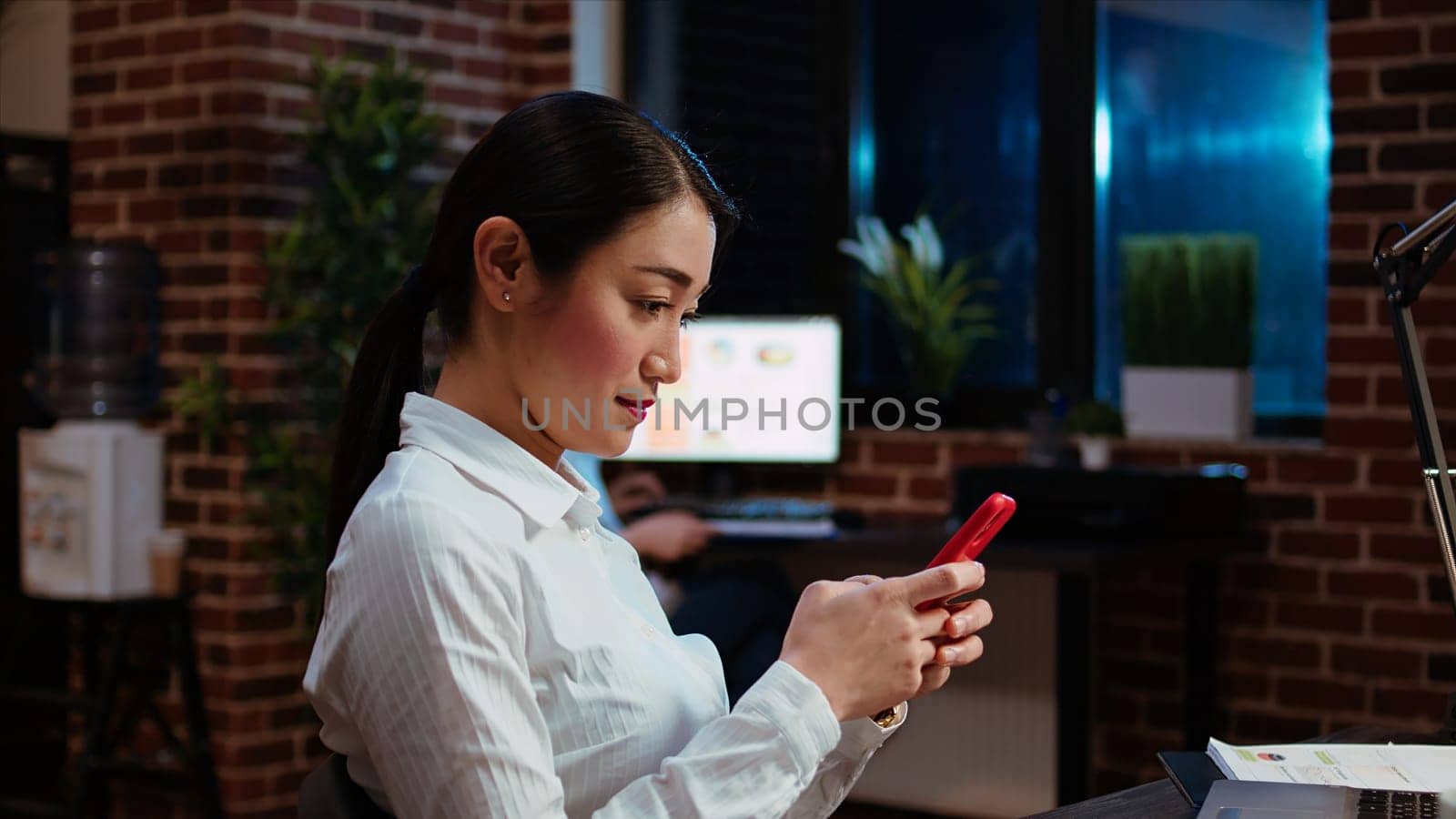 Financial analyst looking at text messages on smartphone, taking break from work with business charts, close up. Panning shot of ecommerce consultant using mobile phone to browse internet in office