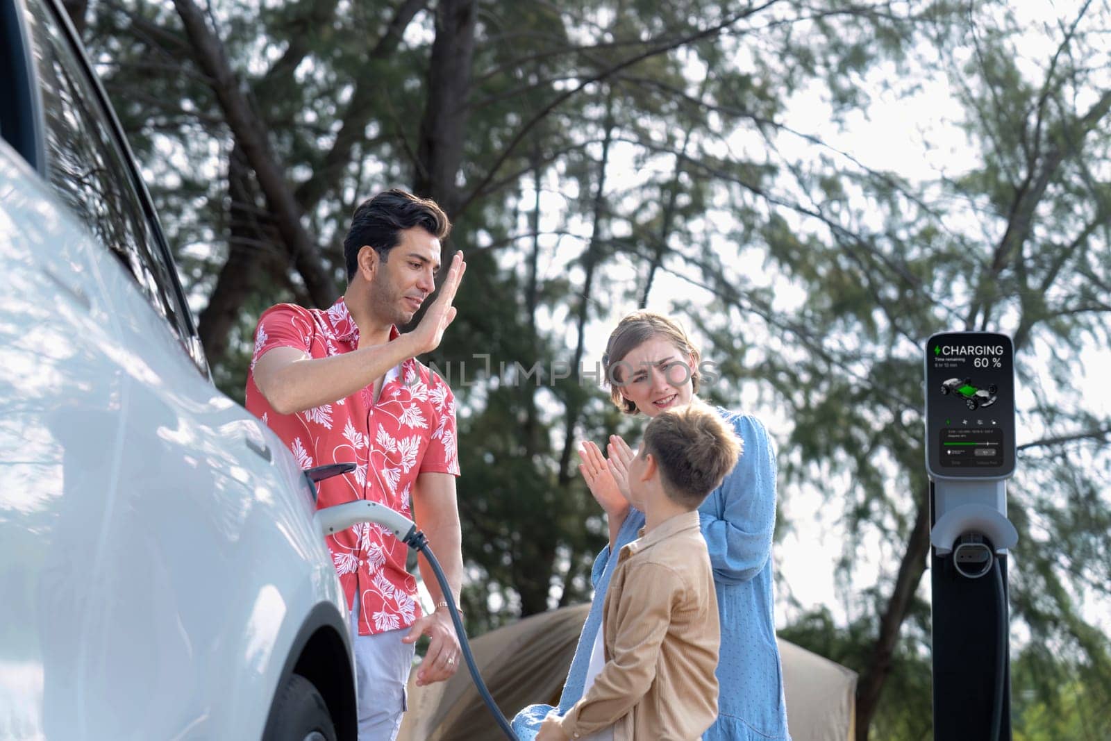 Lovely family recharge EV car with EV charging station in campsite. Perpetual by biancoblue