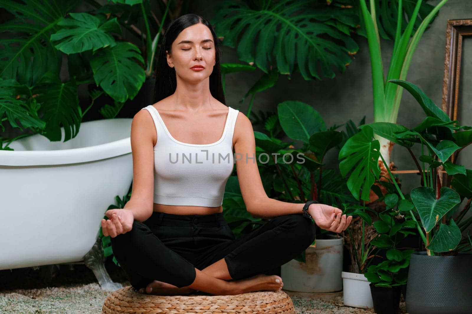 Young woman doing morning yoga and meditation in natural garden with plant leaf, enjoying the solitude and practicing meditative poses. Mindfulness activity and healthy mind lifestyle. Blithe